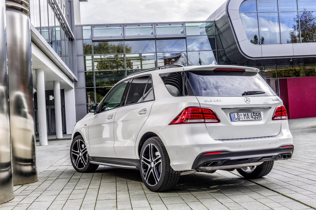 Weißer Mercedes-Benz SUV vor moderner Glasfassade geparkt. Der Wagen steht auf grauen Pflastersteinen und zeigt das Heck des Fahrzeugs.
