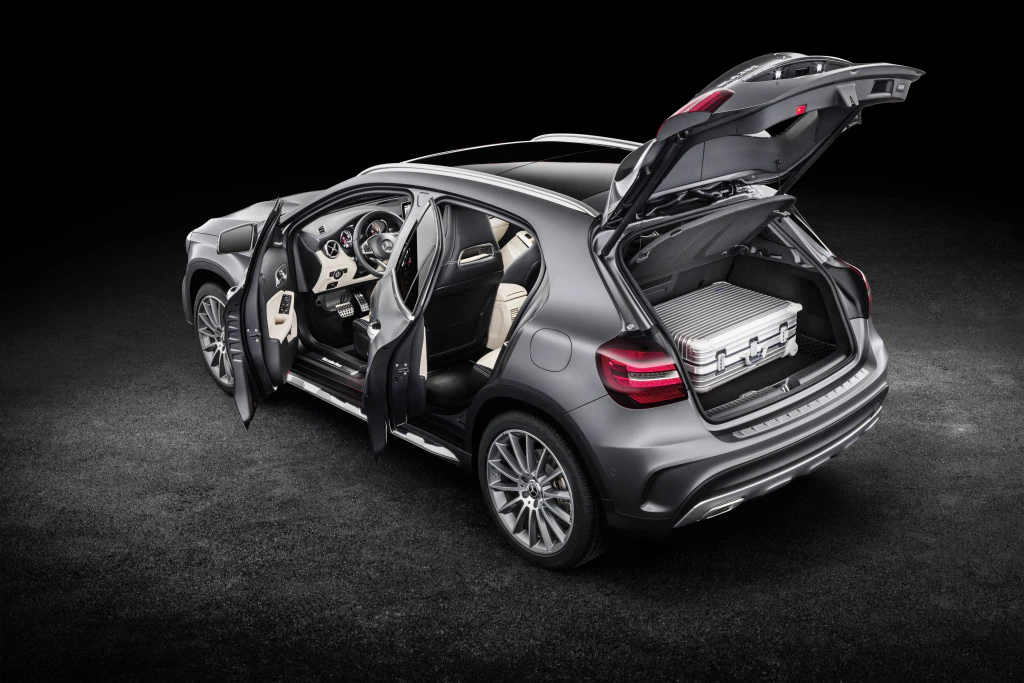 Ein silberner SUV mit geöffneten Türen und Kofferraum, in dem ein Koffer liegt. Sicht auf das luxuriöse Innenraumdesign.