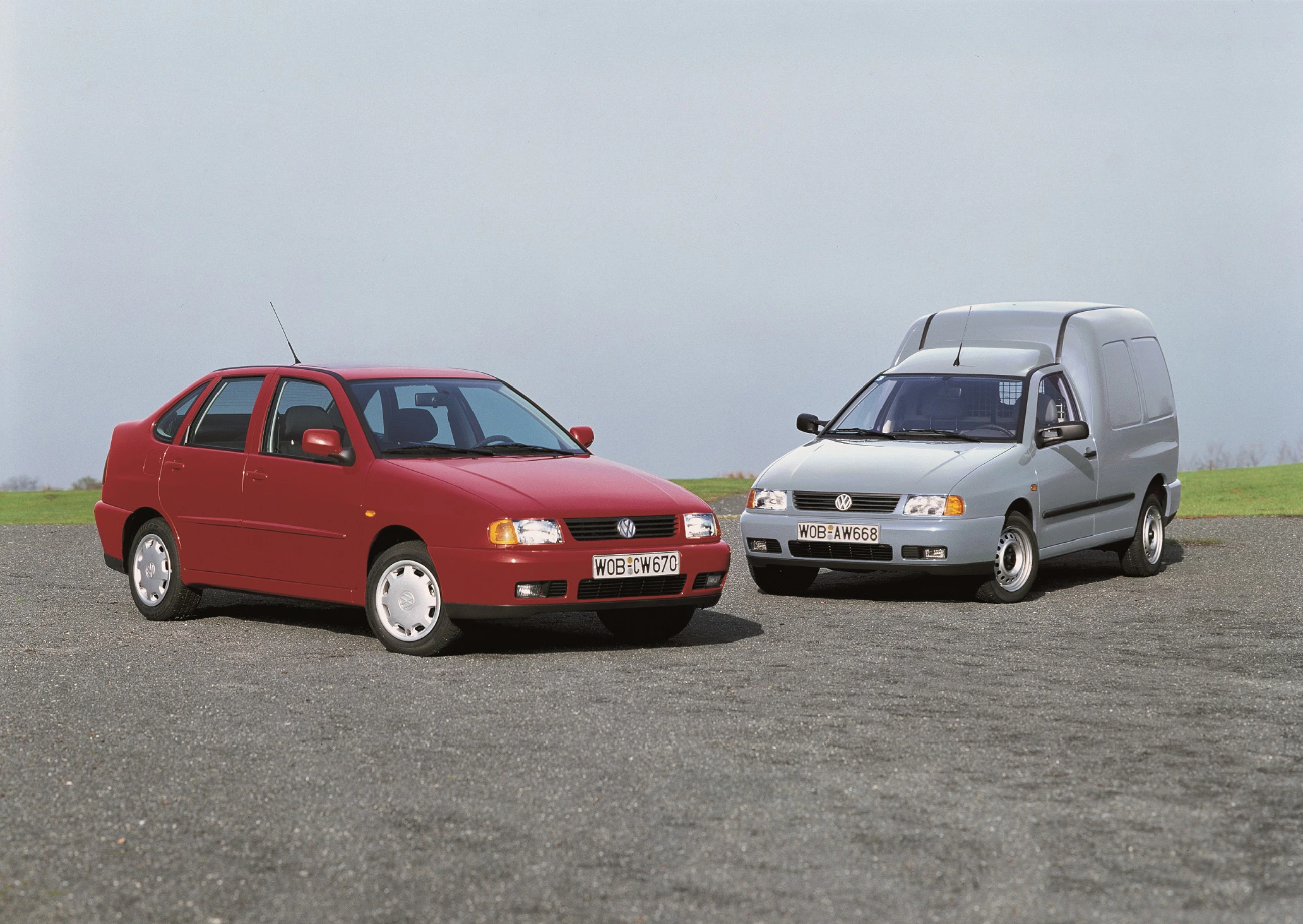 Zwei Autos auf einem Parkplatz: links ein roter SEAT Ibiza, rechts ein silberner SEAT Inca Lieferwagen, bei bewölktem Himmel.