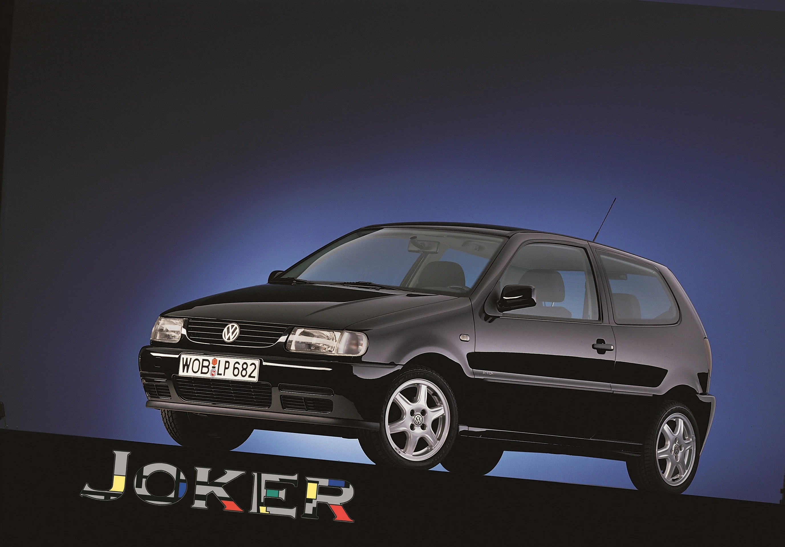 Schwarzer VW Polo Joker auf blauem Hintergrund, Seitenansicht. Automodell mit sportlichem Design und Text "Joker" unten.