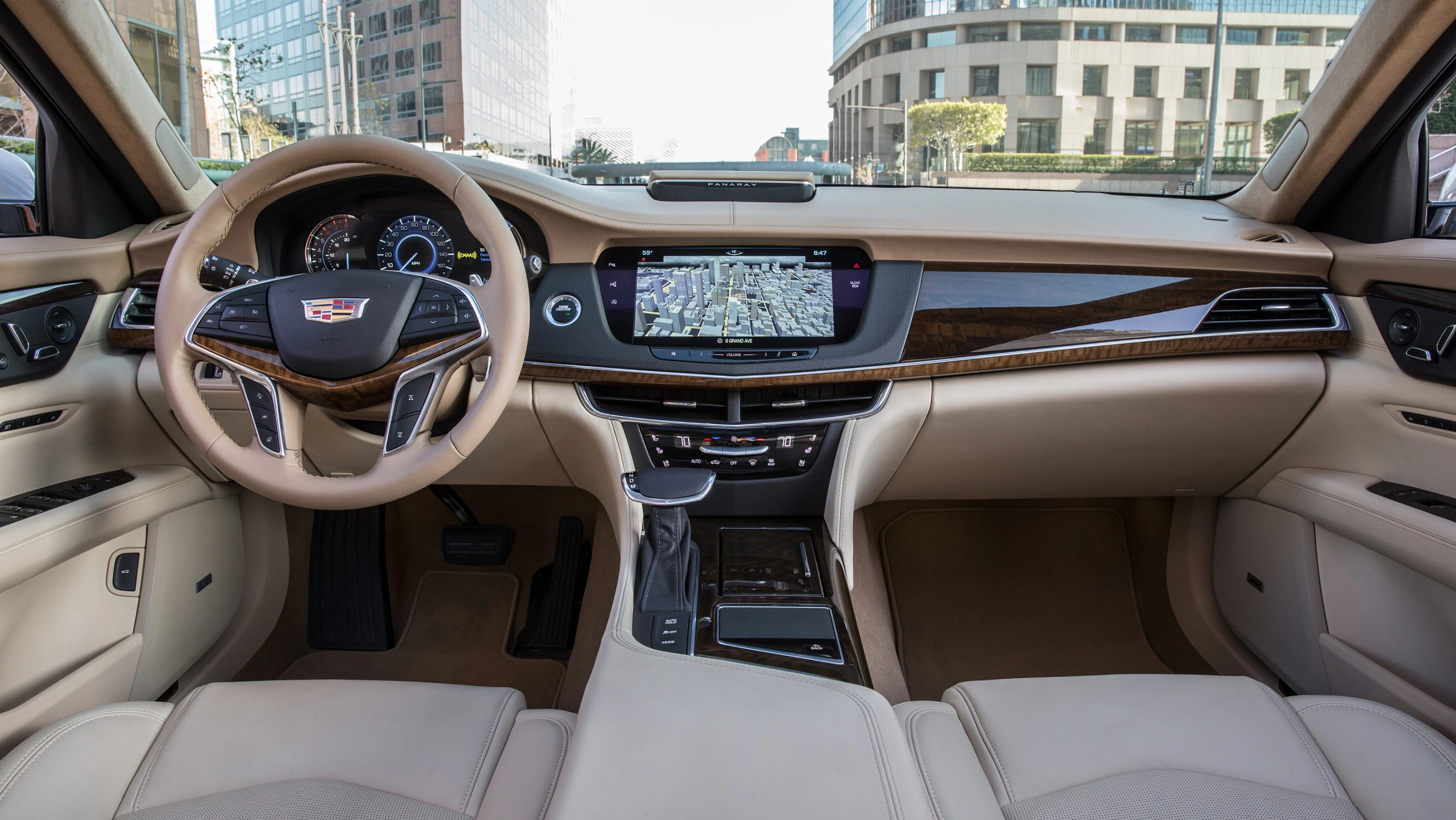 Innenraum eines Luxusautos mit beigem Leder, Holzdetails, einem modernen Lenkrad und einem Touchscreen-Navigationssystem.