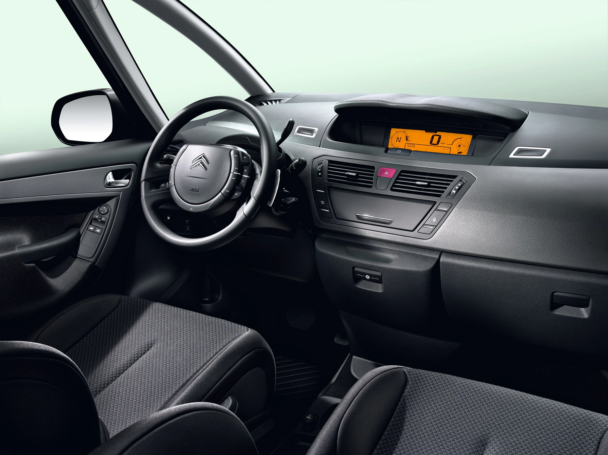 Innenraum eines Autos mit grauem Armaturenbrett, digitalem Display und Lenkrad. Vordersitze sind aus grauem Stoff.
