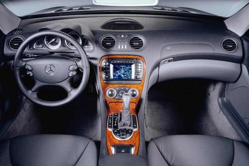 Innenraum eines Mercedes mit Lederinterieur, Holzverkleidung, Multifunktionslenkrad und Navigationsdisplay in der Mittelkonsole.