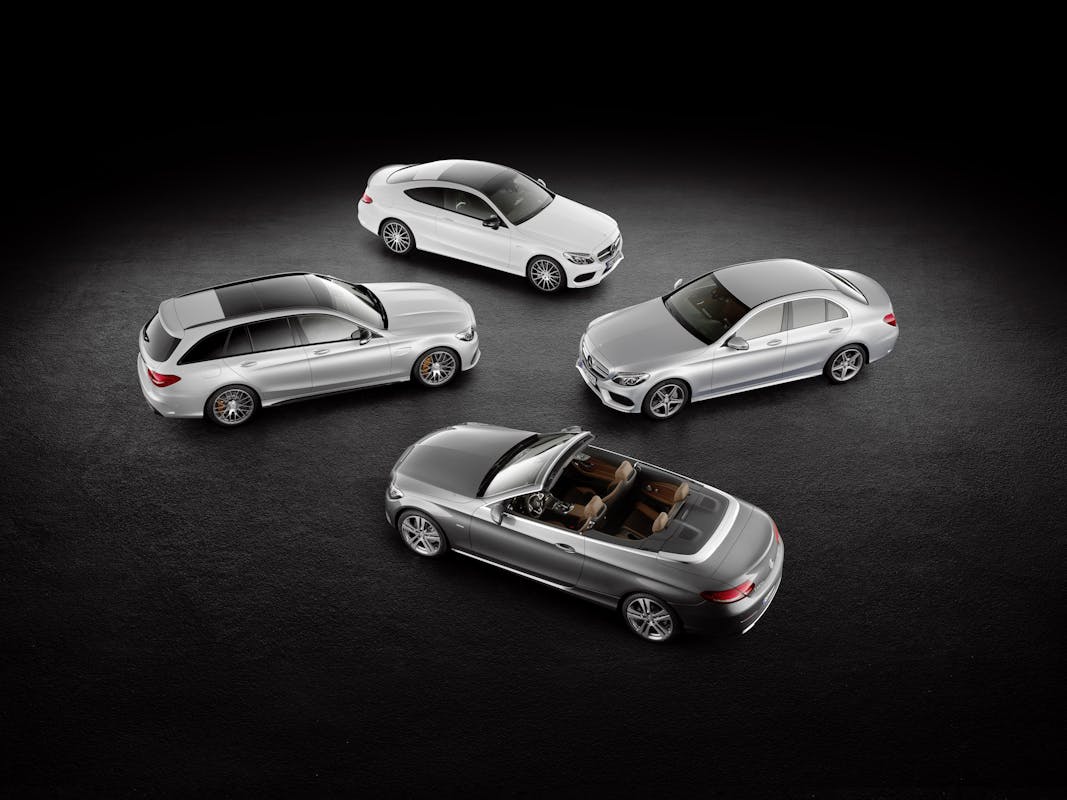 Vier silberne Autos verschiedener Karosserieformen (Limousine, Kombi, Coupé, Cabriolet) stehen auf einem dunklen Hintergrund.