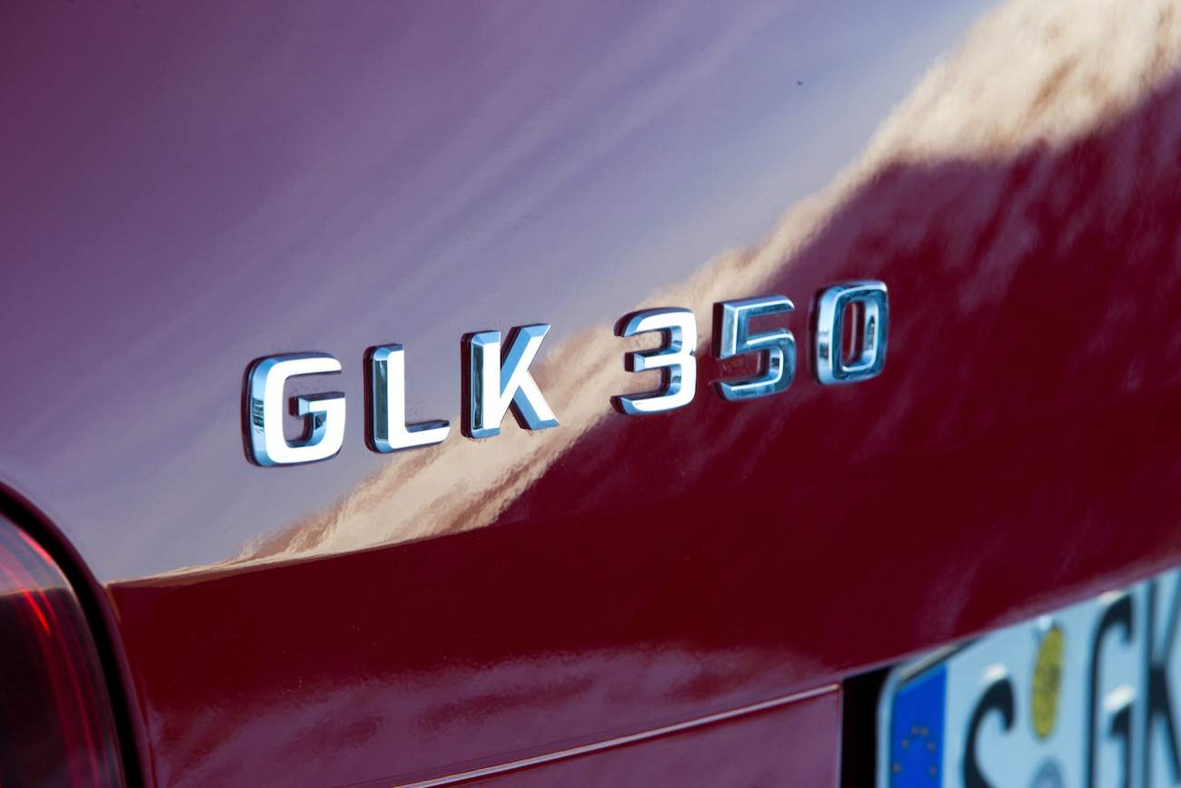 Nahaufnahme des Heckbereichs eines roten Fahrzeugs mit "GLK 350"-Emblem und einem Teil eines EU-Kennzeichens.