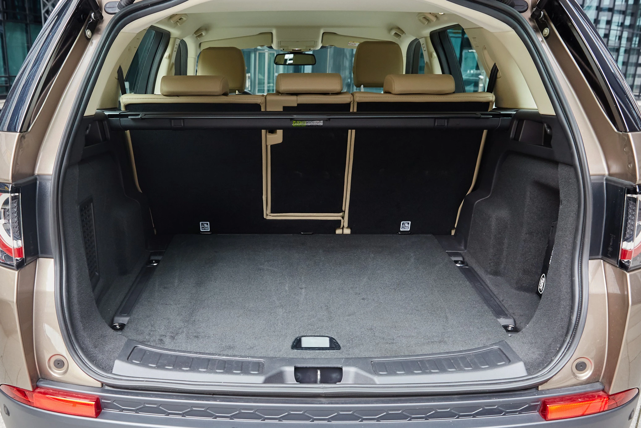 Offener Kofferraum eines SUVs mit umgeklappten Sitzen, die großzügigen Laderaum zeigen. Beige Innenausstattung.