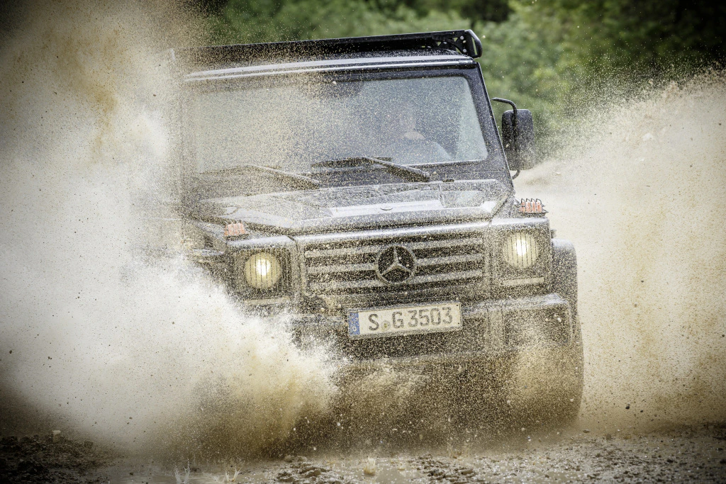 Ein schwarzer Geländewagen fährt spritzend durch schlammiges Wasser auf einer Offroad-Strecke.