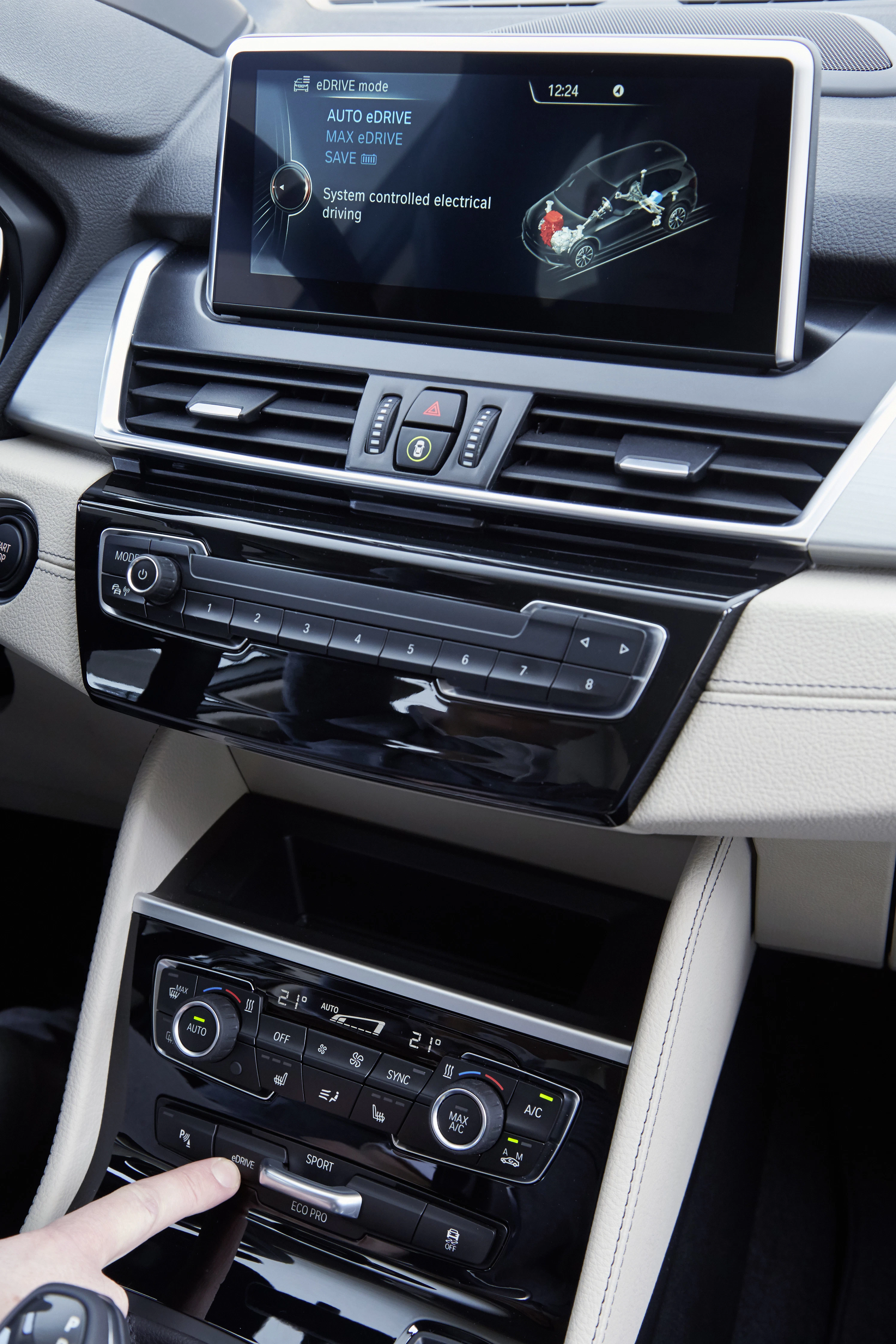 Nahaufnahme eines modernen Autoinnenraums mit Touchscreen-Display, Klimasteuerung und verschiedenen Bedienelementen auf der Mittelkonsole.