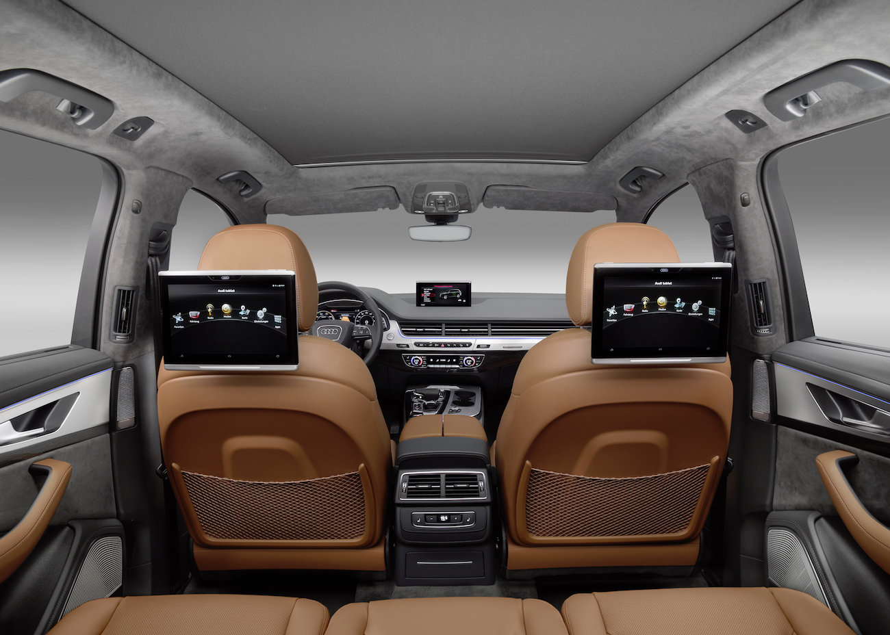 Innenraum eines luxuriösen Autos mit zwei Bildschirmen an den Rückseiten der Vordersitze und brauner Lederausstattung.