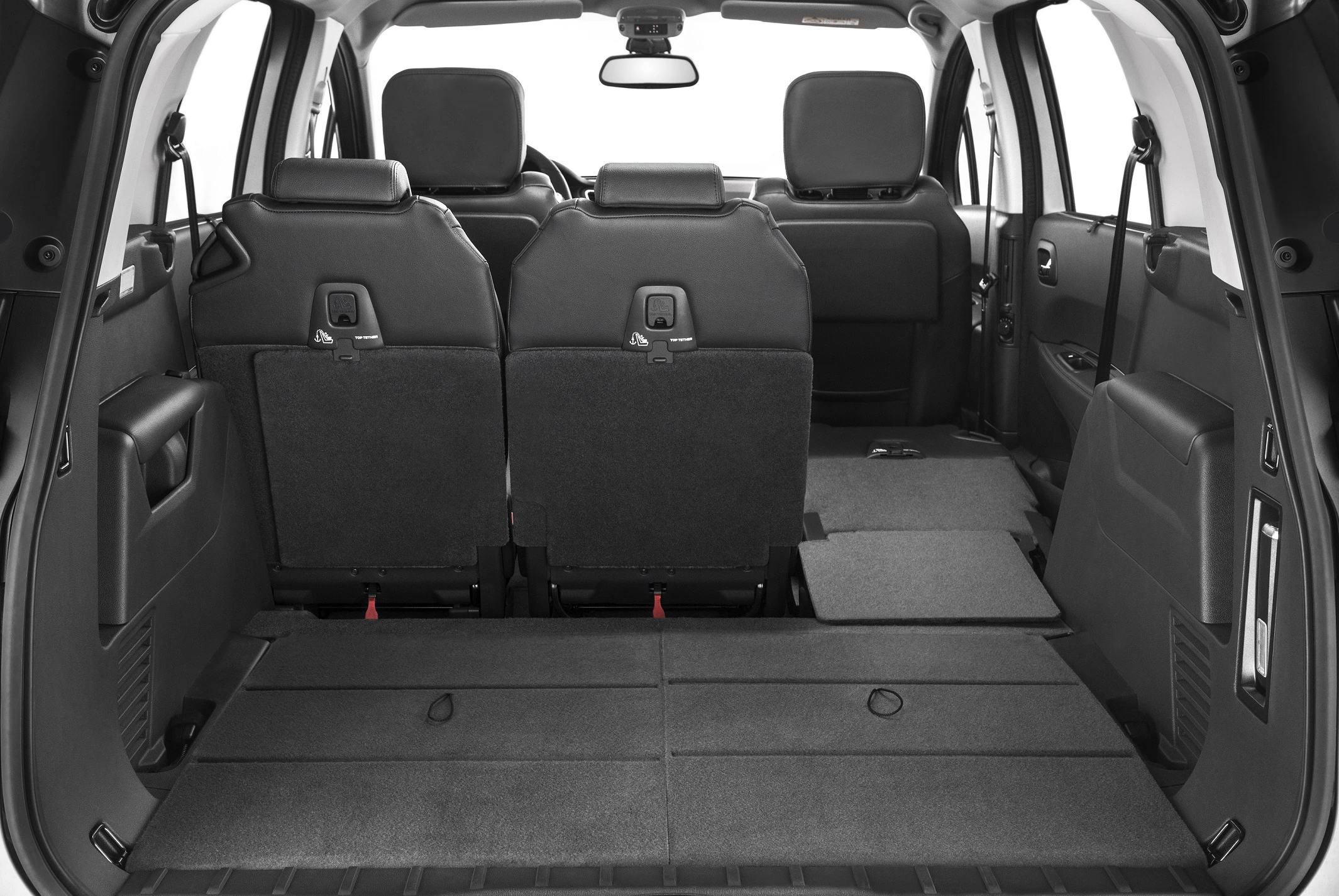 Innenraum eines Autos mit umgeklappten Rücksitzen, die den Kofferraum vergrößern. Sicht von hinten, schwarz-graue Stoffpolsterung.
