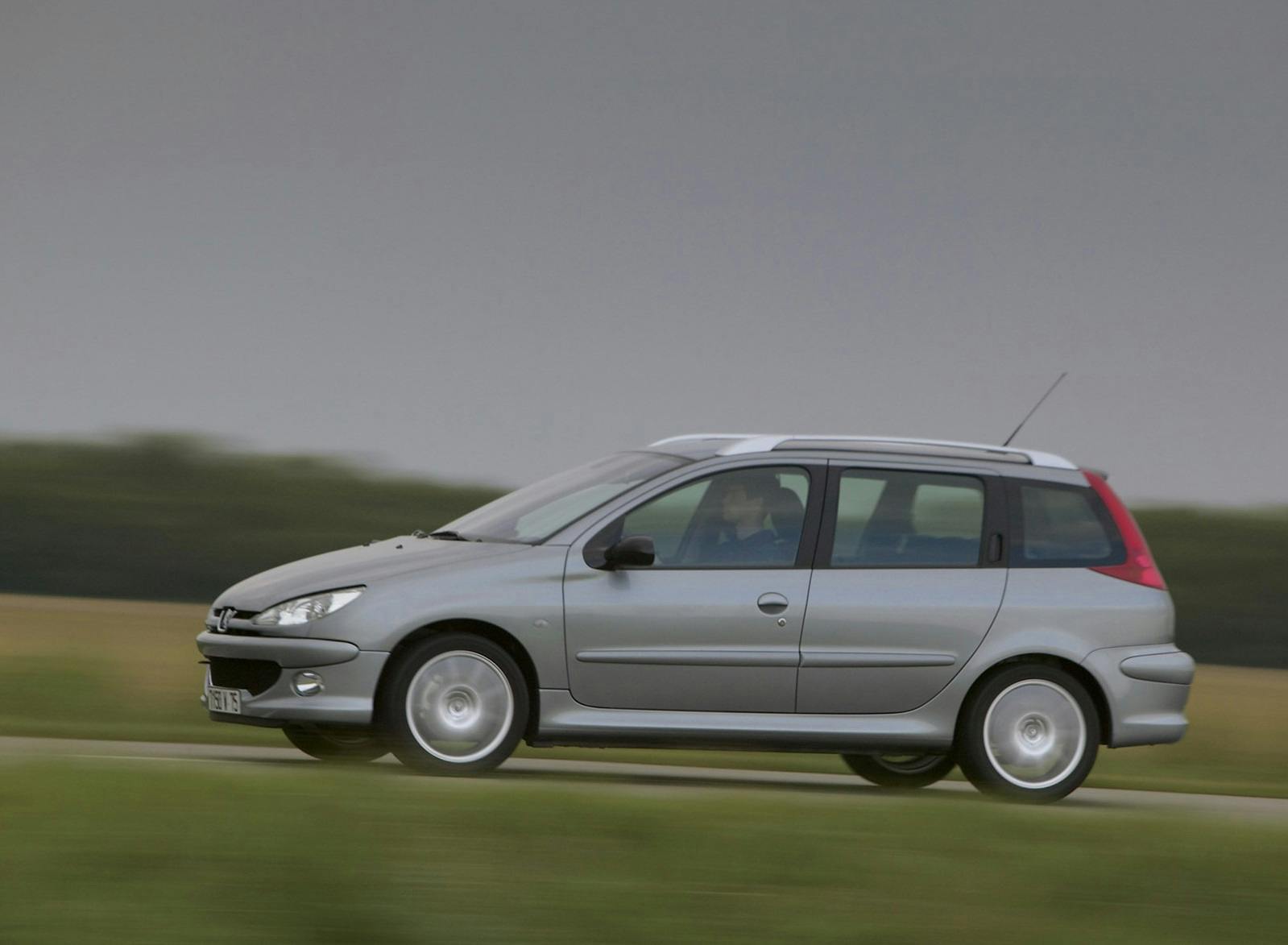 Silberner Kombi fährt schnell auf einer Landstraße mit unscharfem Hintergrund.