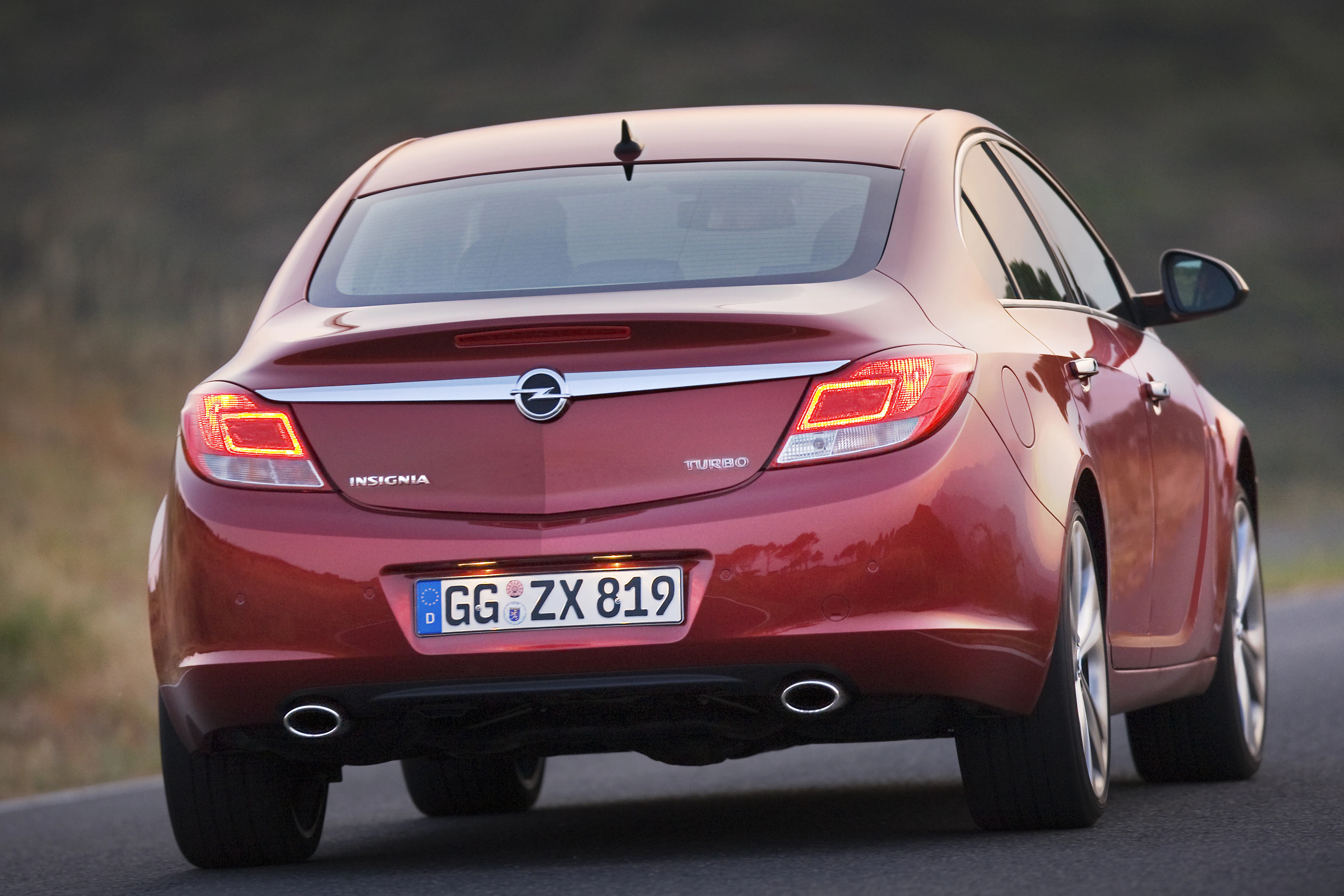 Roter Opel Insignia Turbo auf einer Landstraße, Rückansicht. Nummernschild: GG ZX 819. Fahrzeug hat Doppelauspuffrohre.