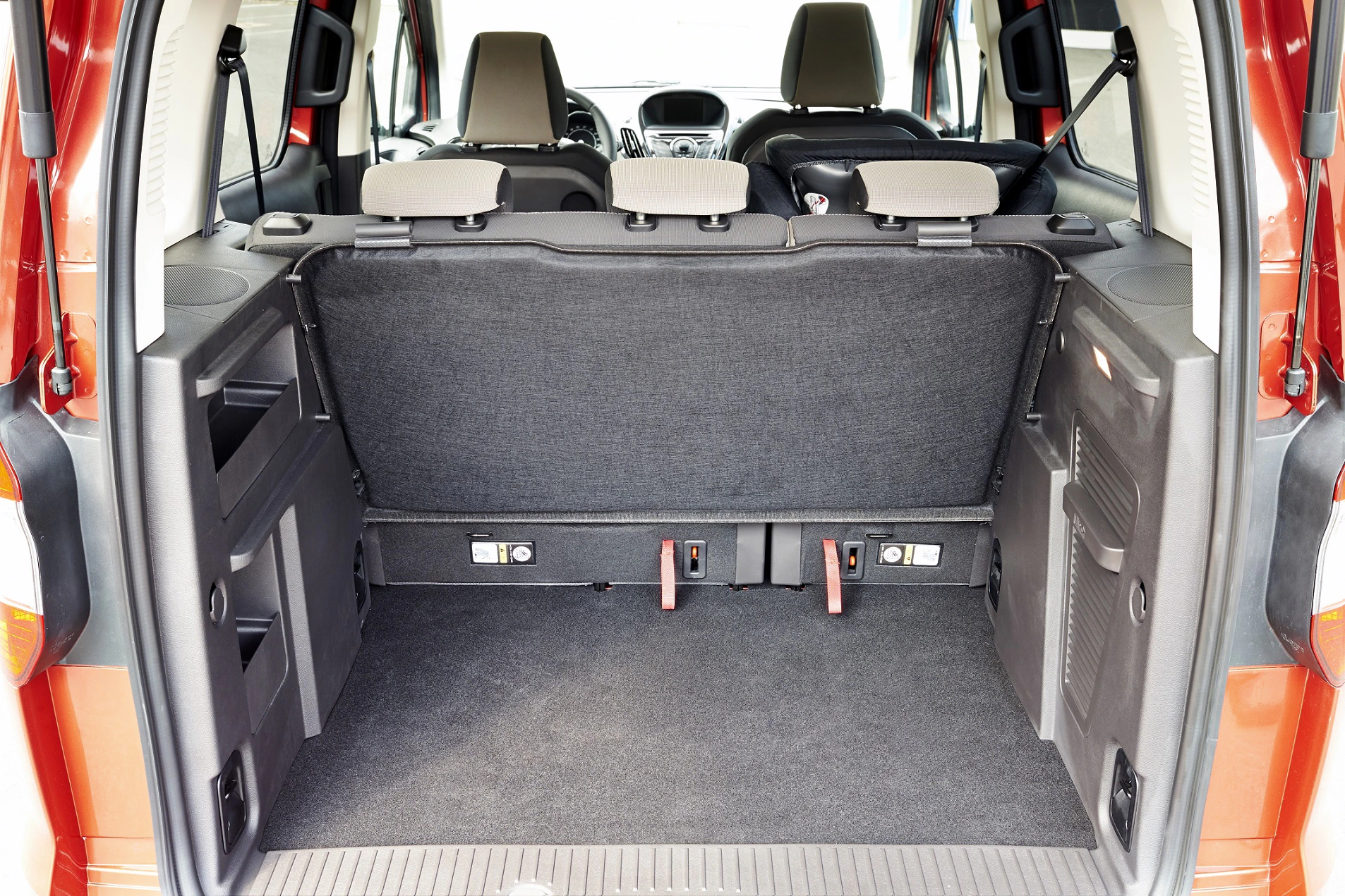 Kofferraum eines roten Autos mit umgeklappten Rücksitzen, die viel Laderaum bieten. Innenansicht von hinten.