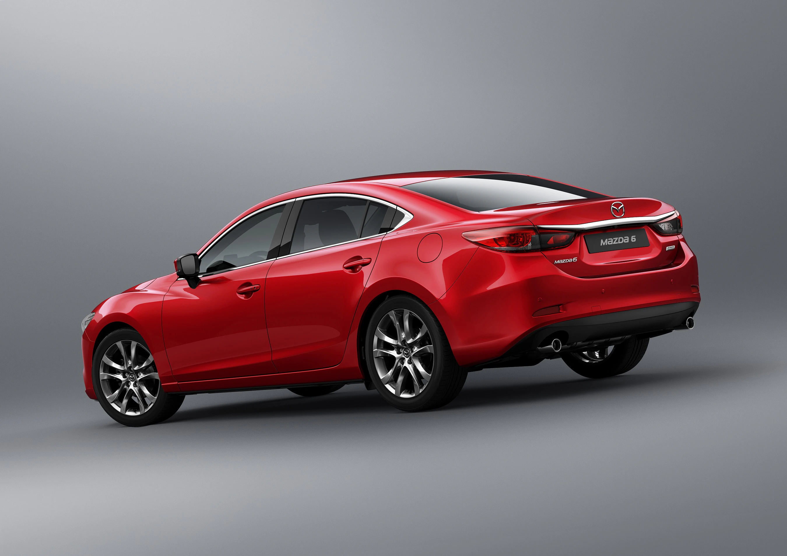 Roter Mazda6 in Seitenansicht vor grauem Hintergrund, sportliches Design, silberne Felgen und Doppelauspuff.