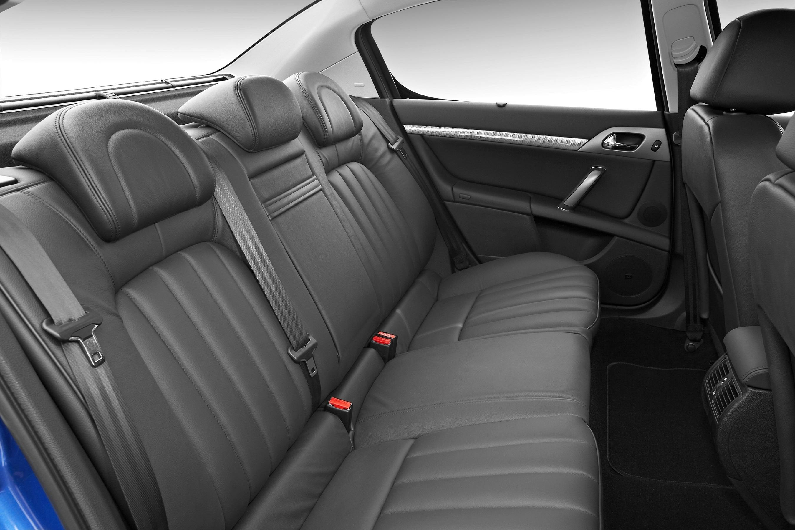 Rückbank eines Autos mit schwarzer Lederpolsterung, drei Kopfstützen und Sicherheitsgurten, Innenraum in elegantem Design.