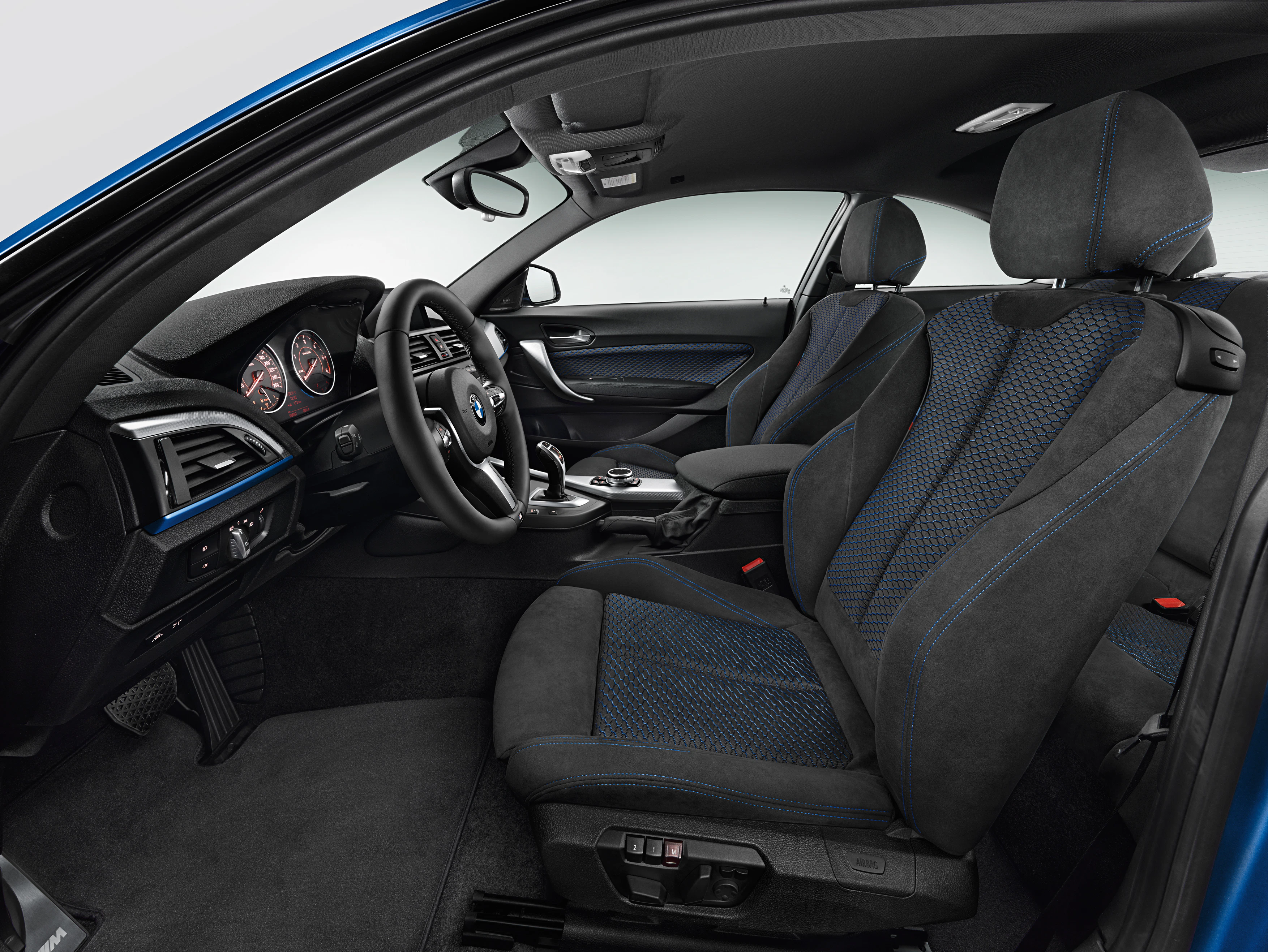 Innenraum eines Autos mit schwarzen Ledersitzen, blauen Akzenten, modernem Armaturenbrett und Sportlenkrad.