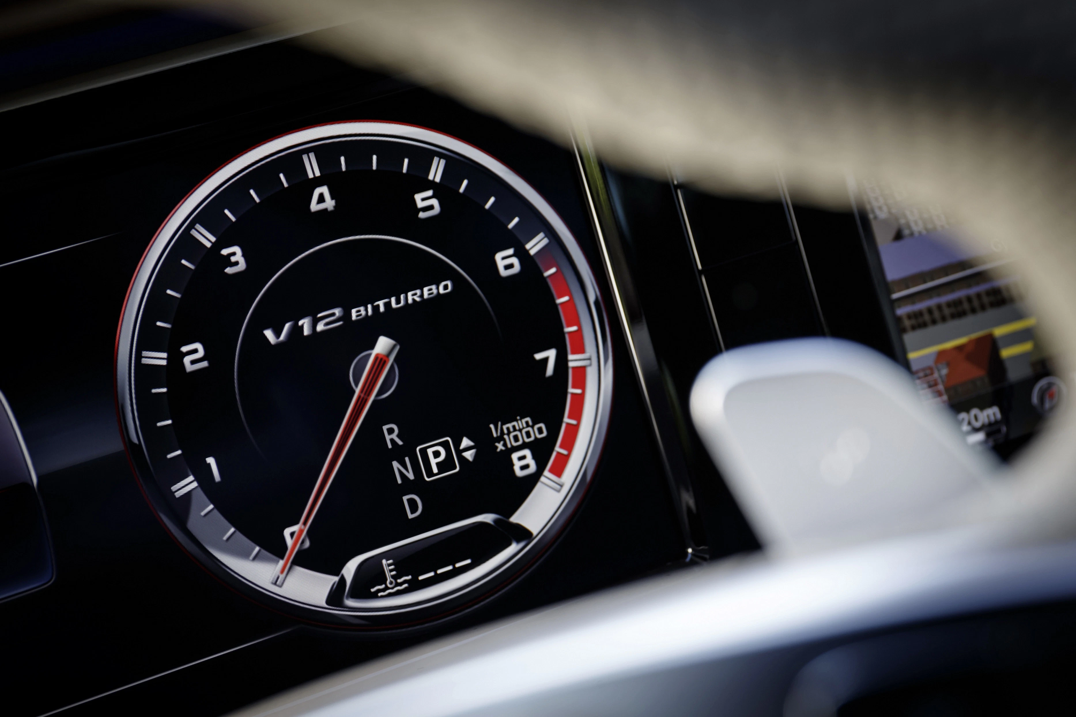 Nahaufnahme eines Autotachometers mit V12 Biturbo-Anzeige, Gangwahl (P, R, N, D) und Tachonadel bei ca. 800 U/min.