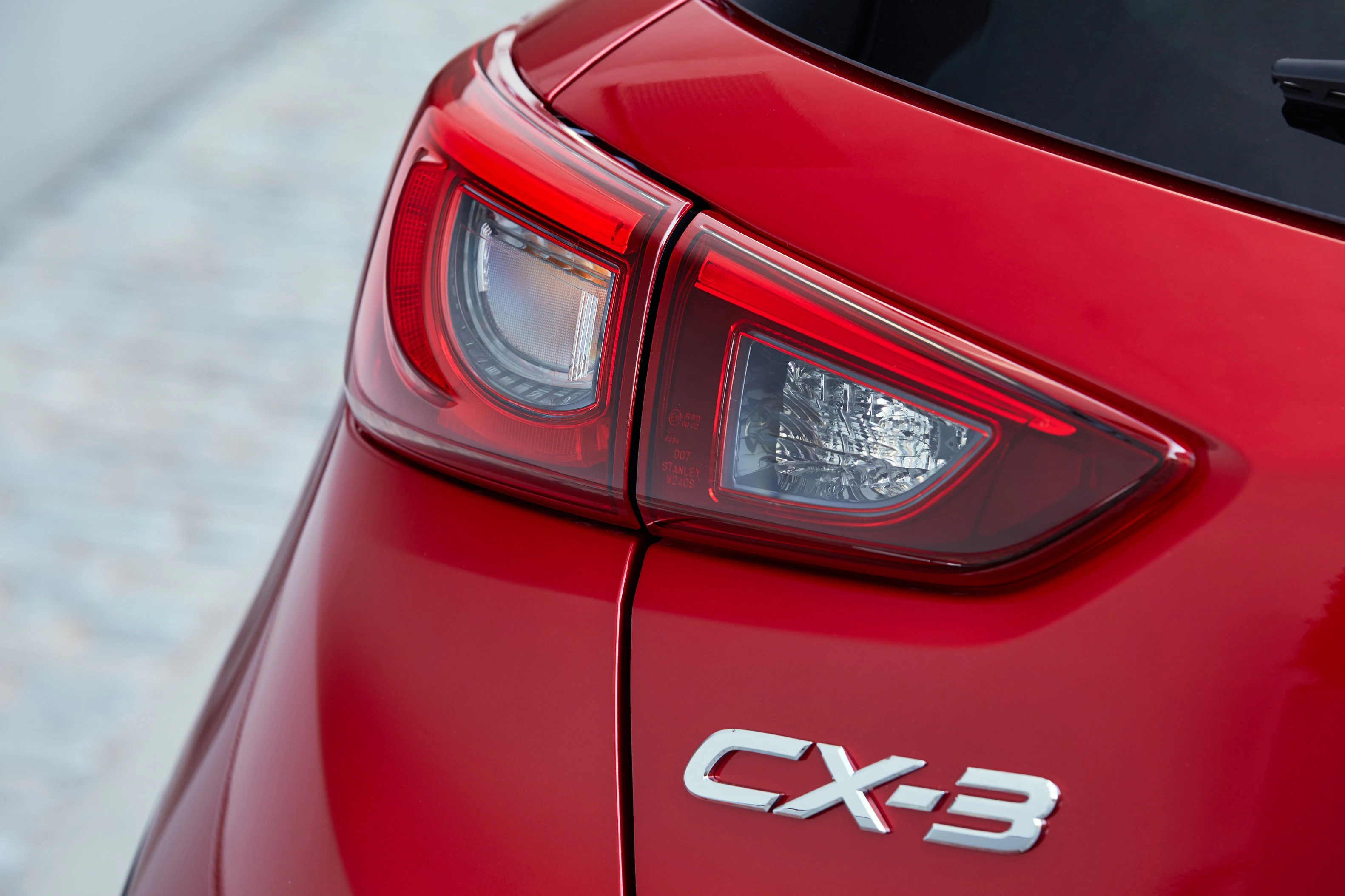 Nahaufnahme des Rücklichts und des Emblems "CX-3" eines roten Mazda-Autos. Modernes Design und glänzende Lackierung.