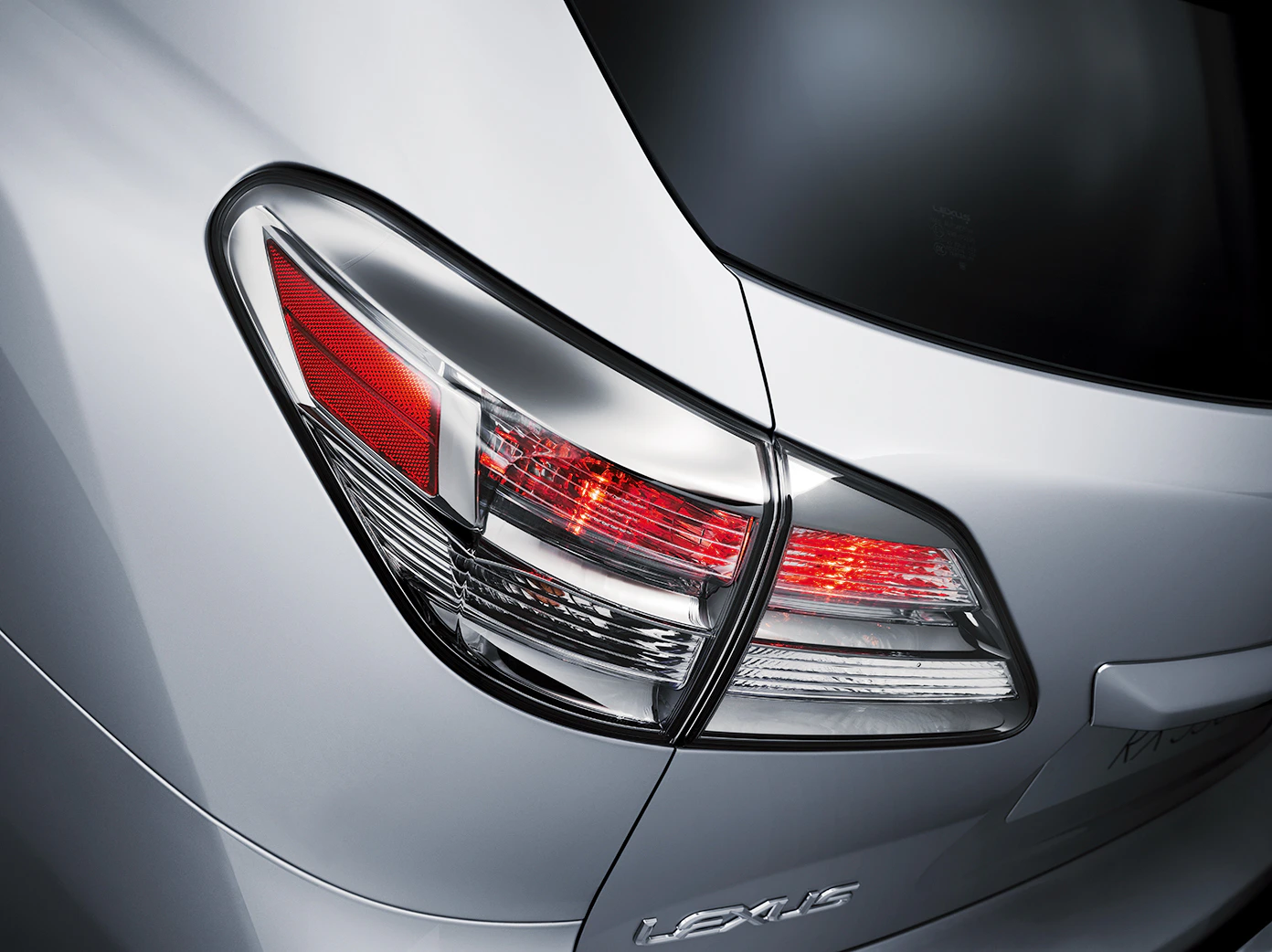 Nahaufnahme eines silbernen Lexus-Heckleuchtendesigns mit auffälligen roten und klaren Lichtelementen.