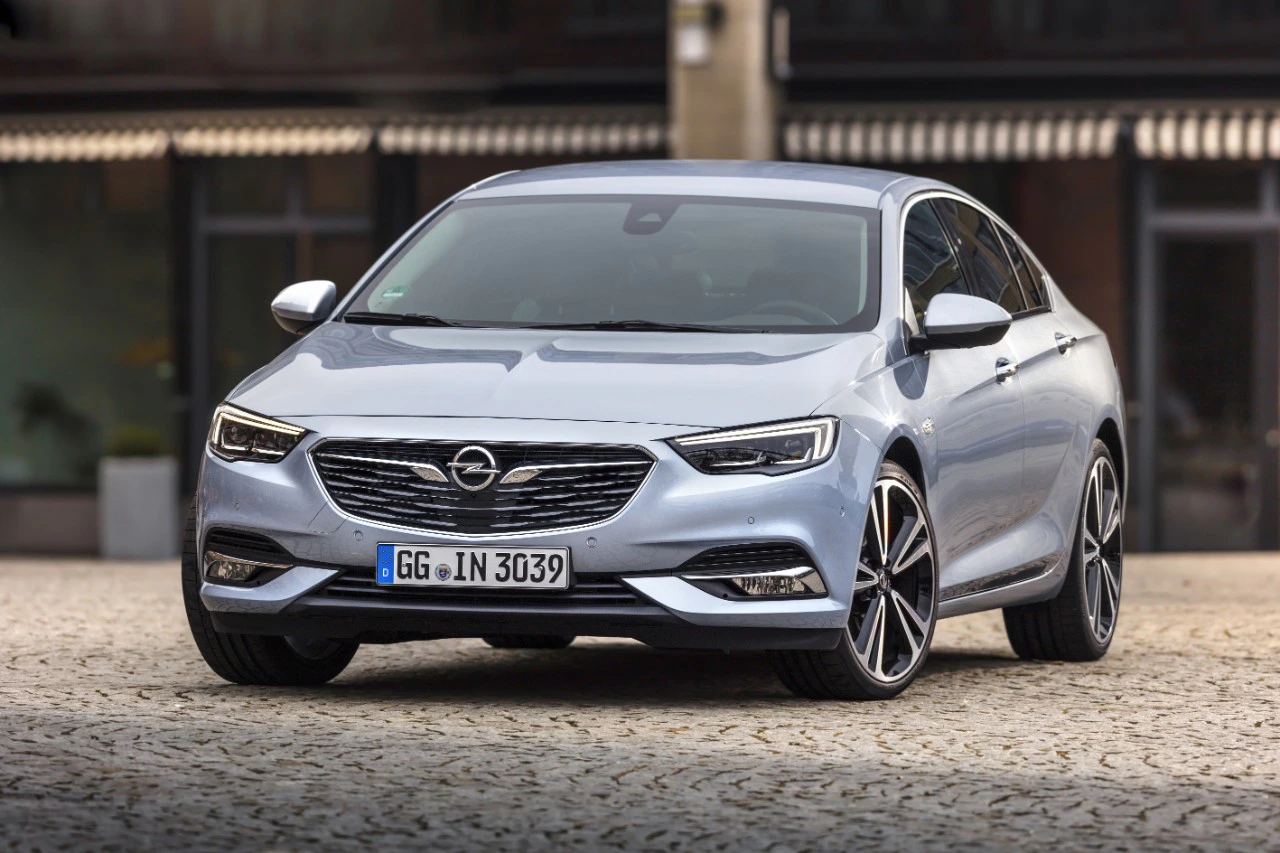 Silberner Opel Insignia in städtischer Umgebung, seitlich vorne fotografiert. Elegantes Design mit markanten Felgen und Kühlergrill.