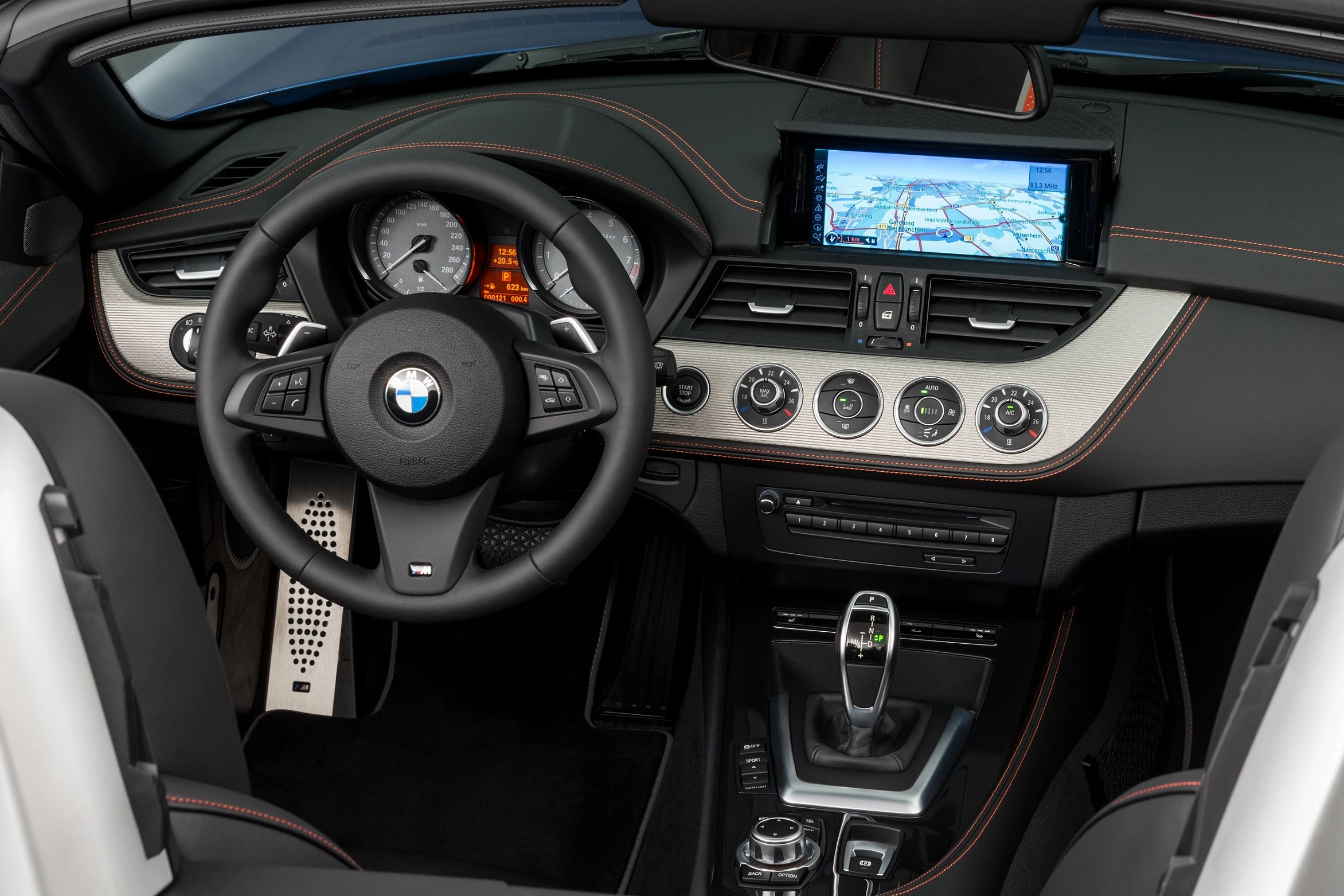 Innenraum eines BMW mit Lederlenkrad, Tachometer, Navigationssystem auf dem Display, Klimasteuerung und Automatikschaltung.
