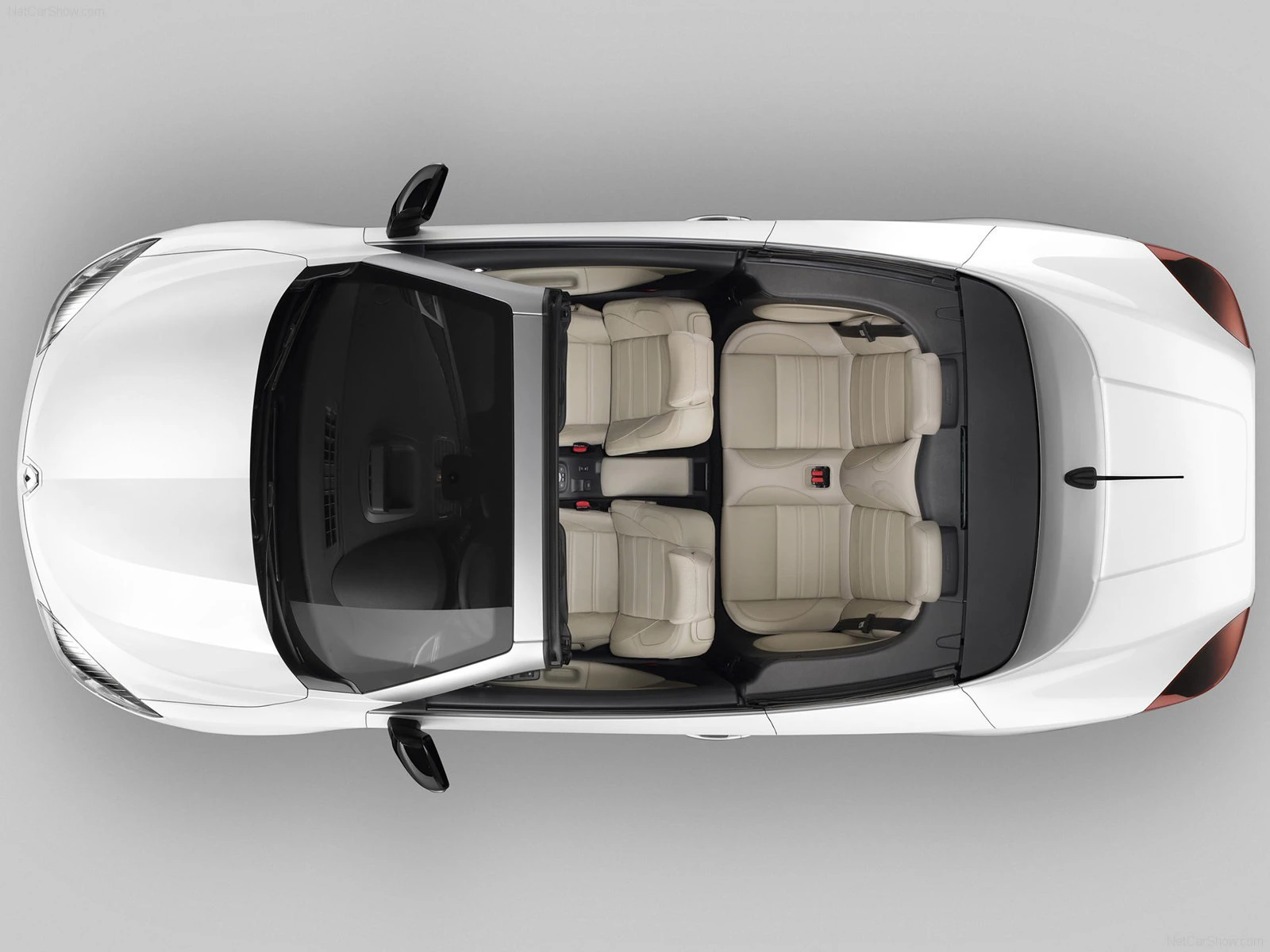 Draufsicht auf ein weißes Auto mit offenem Dach, das vier beige Ledersitze zeigt.