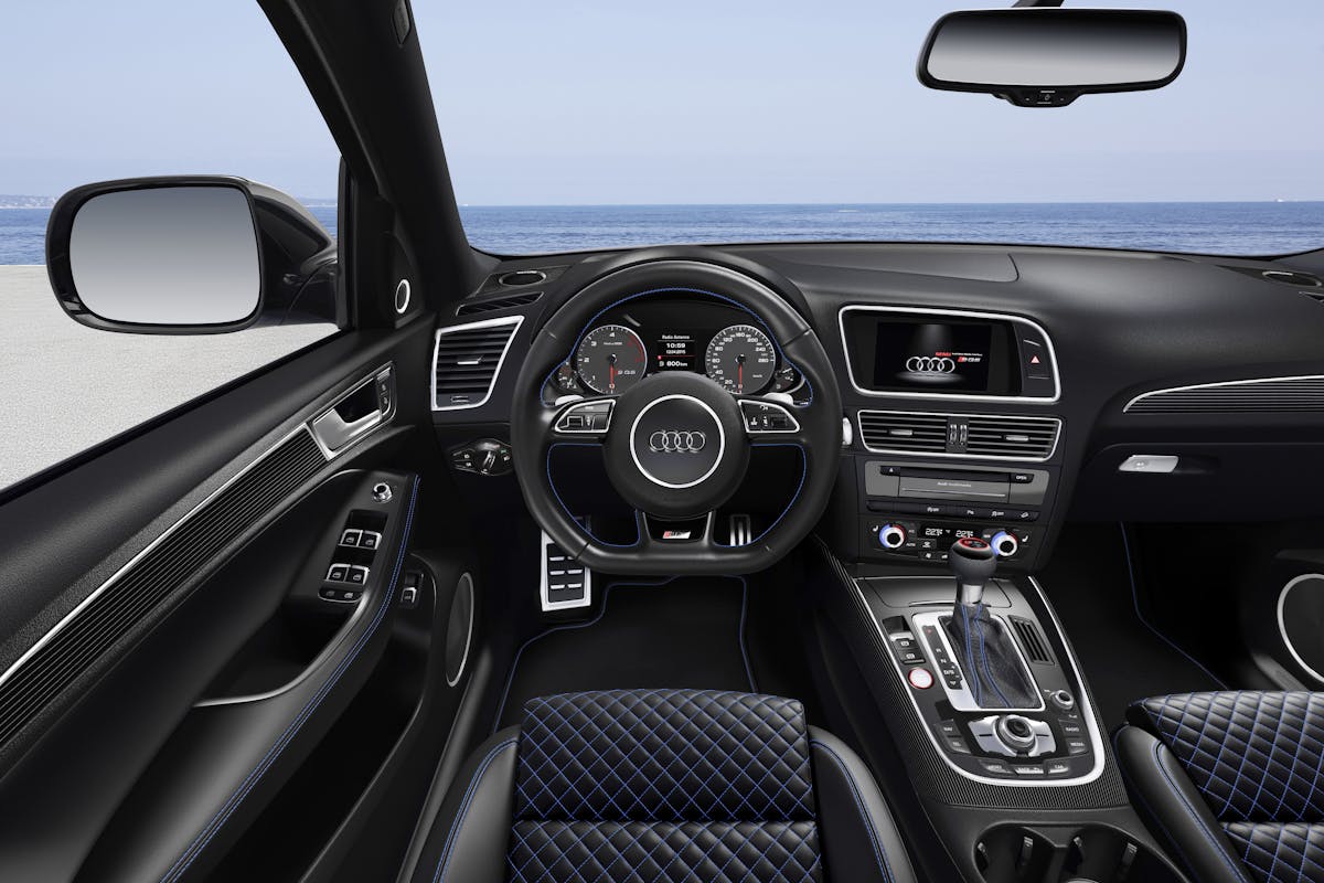Innenansicht eines Audi-Autos am Meer mit Cockpit, Lenkrad, Schalthebel und Multimedia-Display.