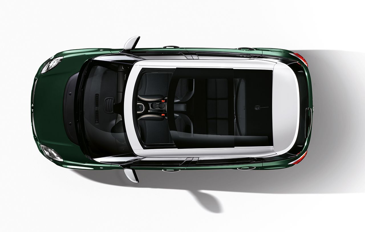 Draufsicht auf ein grünes Auto mit Panoramadach vor weißem Hintergrund.