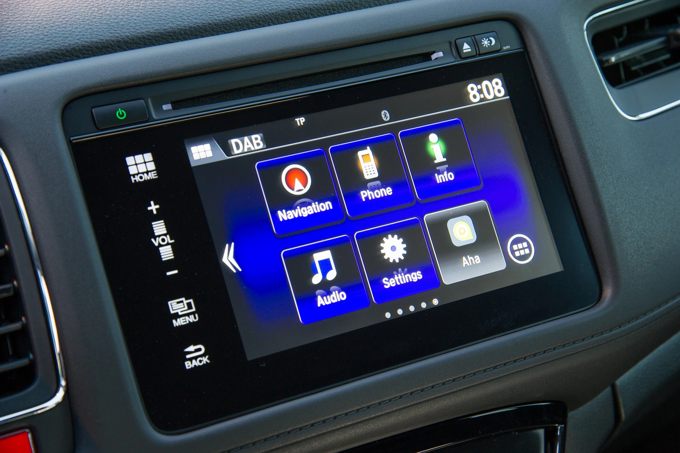 Nahaufnahme eines Autodisplays mit Touchscreen. Zu sehen sind Symbole für Navigation, Telefon, Info, Audio, Einstellungen und mehr.