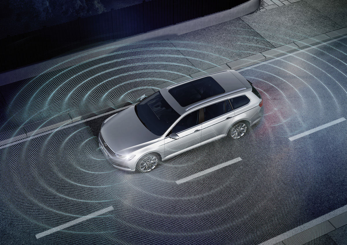 Silbernes Auto auf einer Straße, umgeben von grafischen Wellenlinien, die moderne Sensortechnologie zur Umgebungserkennung darstellen.