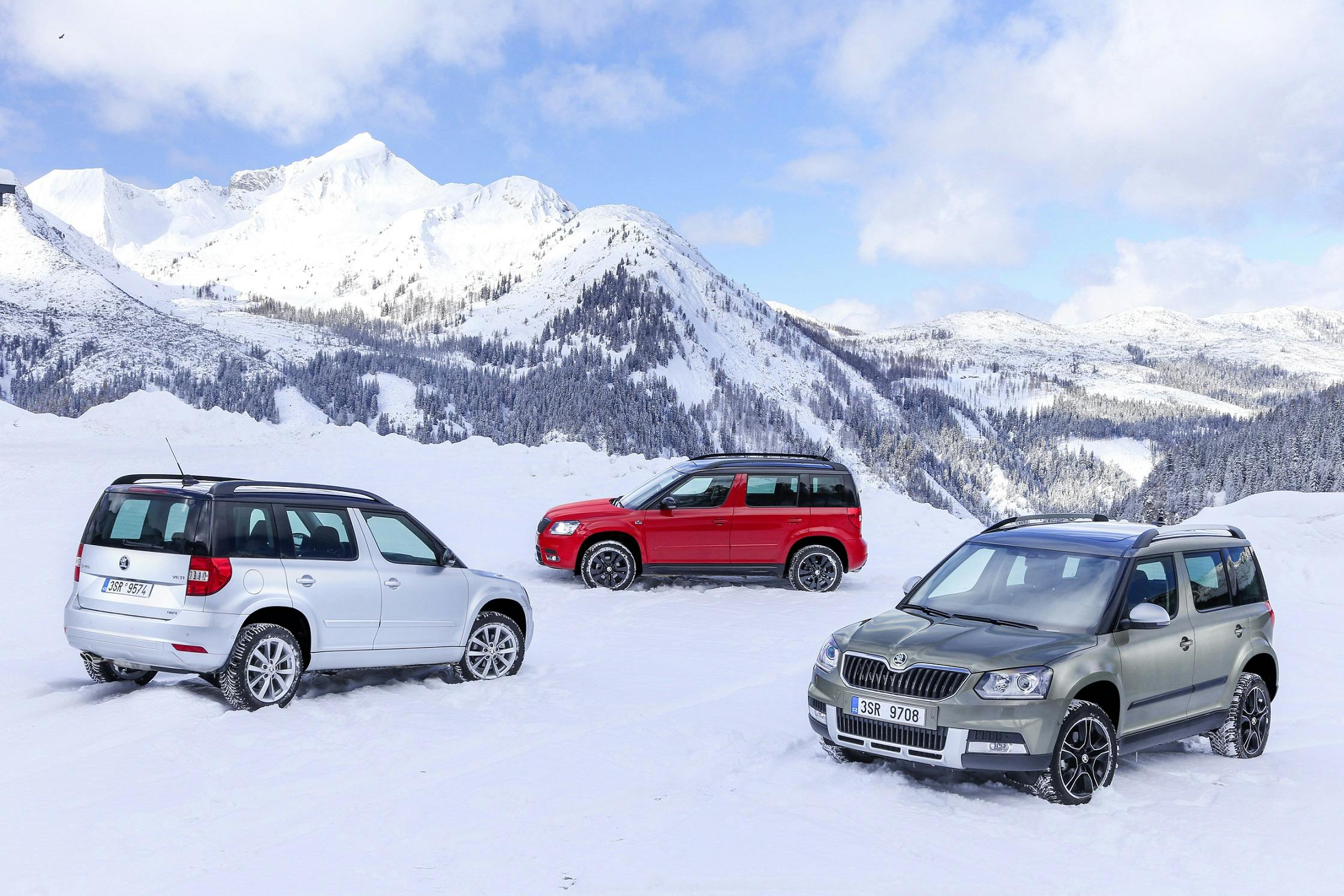 Drei SUVs im Schnee vor einer Bergkulisse: ein silberner, ein roter und ein grauer Wagen. Schnee bedeckt die Landschaft, Himmel ist klar.