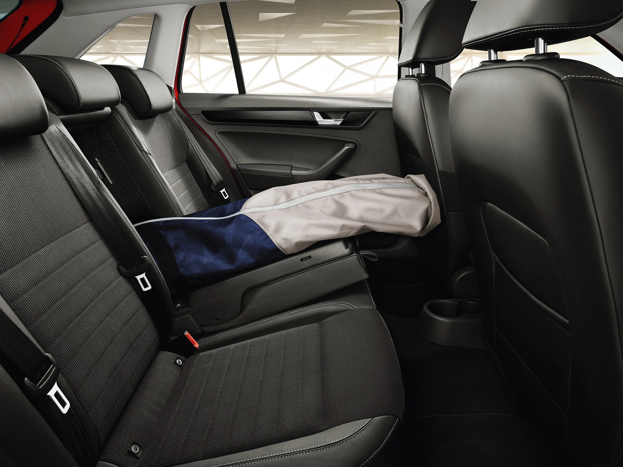 Rückbank eines Autos mit heruntergeklappter Sitzlehne für lange Gegenstände, die in den Kofferraum ragen, in stilvollem schwarzen Lederinterieur.