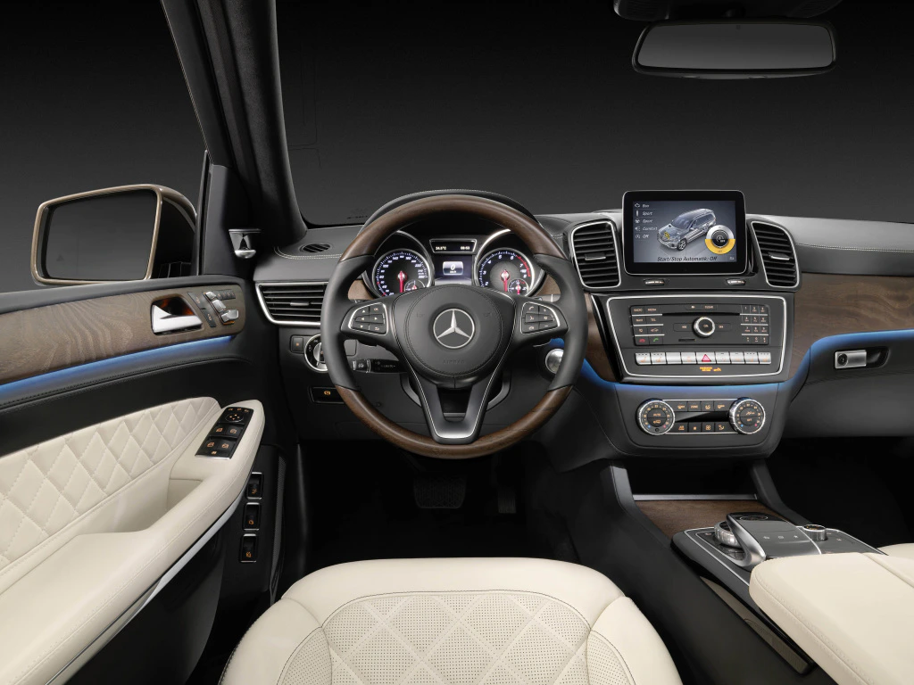 Lenkrad und Armaturenbrett eines Mercedes-Benz mit Holz- und Lederdetails. Touchscreen und moderne Instrumente im Innenraum.