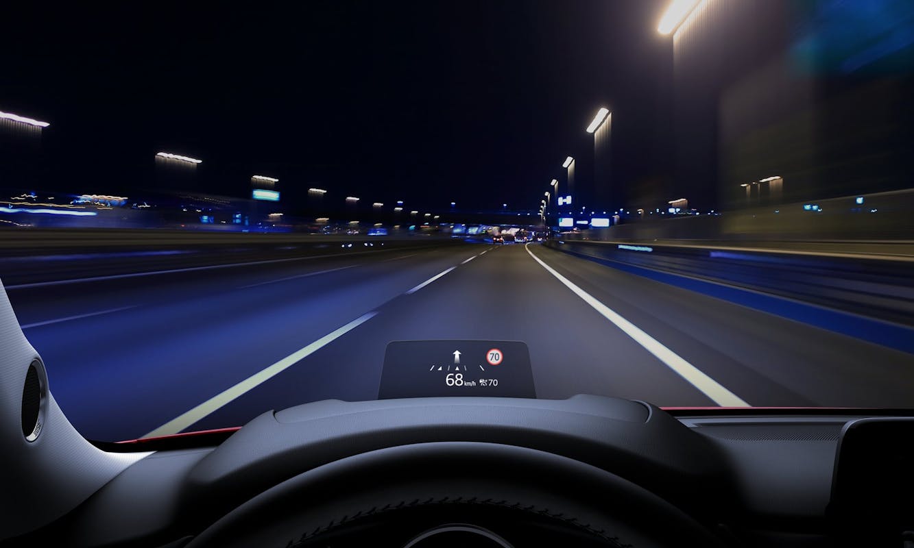 Nachtsicht aus einem Auto auf einer Autobahn. Die Geschwindigkeit wird mit 68 km/h auf einem digitalen Bildschirm projiziert.