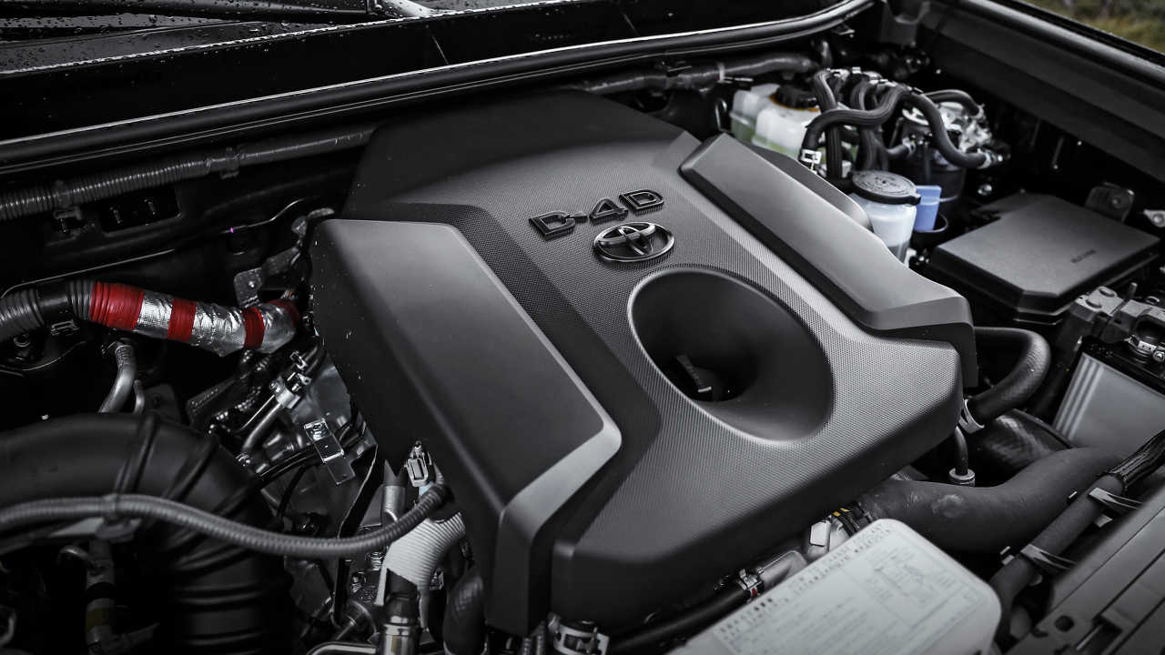 Nahaufnahme eines Toyota D-4D Motors, umgeben von Schläuchen und Komponenten im Motorraum eines Fahrzeugs.