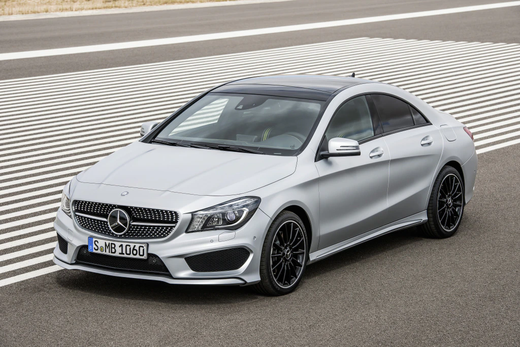 Silberner Mercedes-Benz auf einer Straße mit Zebrastreifen. Sportliches Design, schwarze Felgen, modernes Erscheinungsbild.