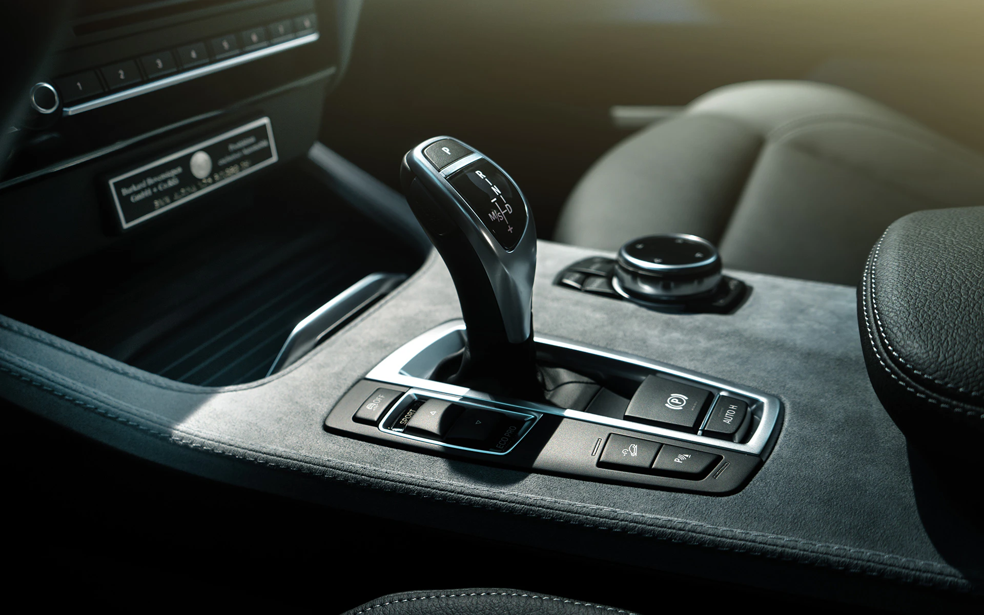 Automatik-Schaltknüppel eines modernen Autos mit umliegenden Bedienelementen im eleganten Innenraum.