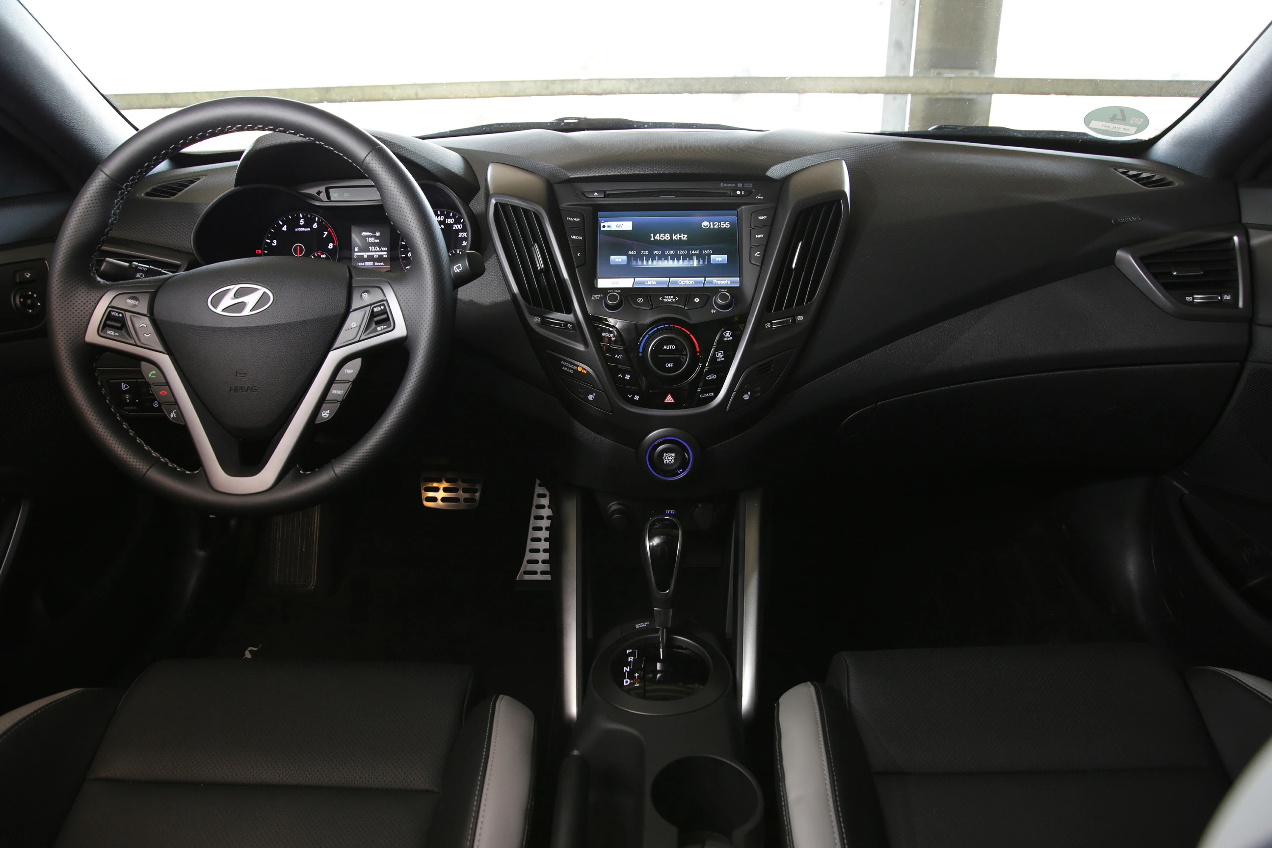 Innenraum eines Autos mit schwarzem Armaturenbrett, Touchscreen-Display, Multifunktionslenkrad und Automatikschaltung.