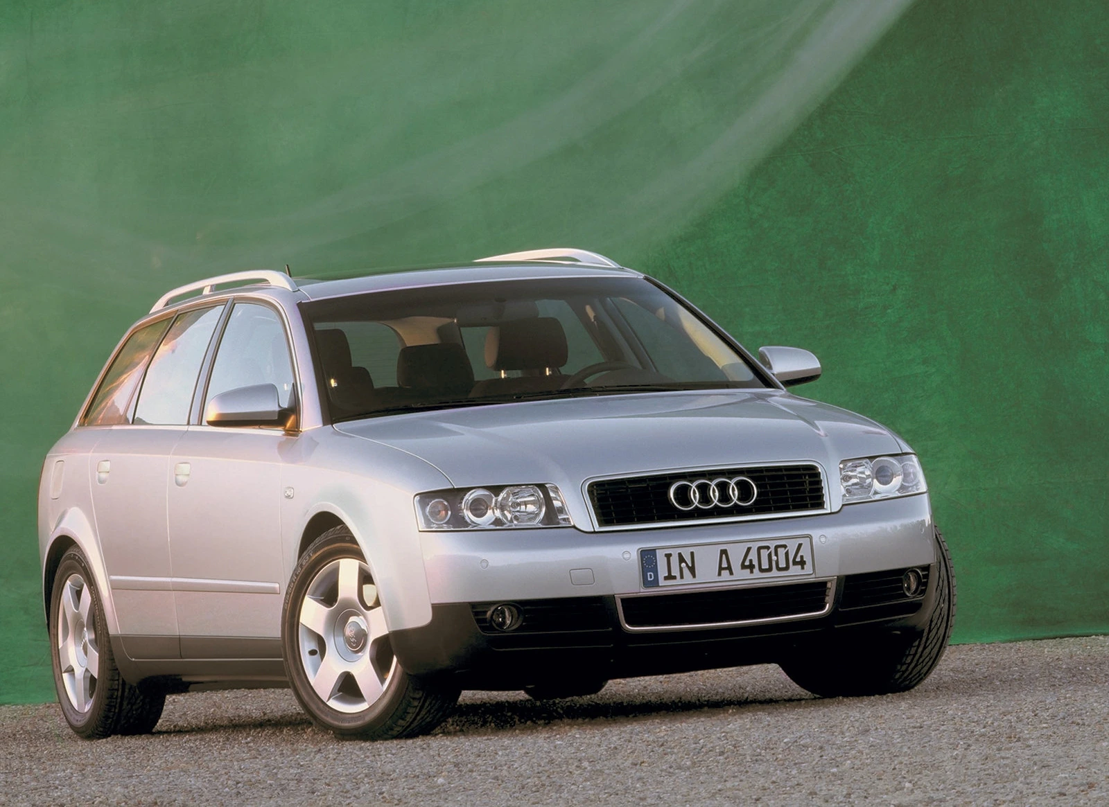 Silberfarbener Audi A4 Kombi vor grünem Hintergrund, schräg von vorne aufgenommen.