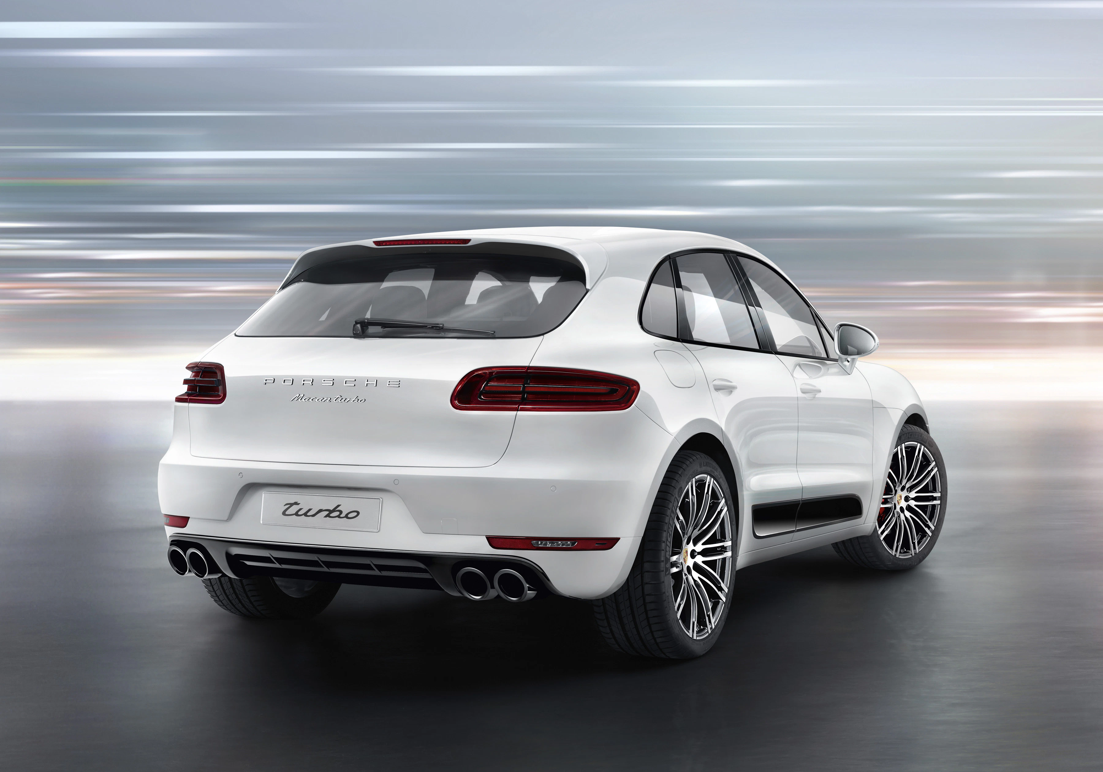 Weißer SUV mit der Aufschrift "Turbo" auf dem Heck. Der Wagen steht in einer dynamischen Umgebung, die Geschwindigkeit suggeriert.