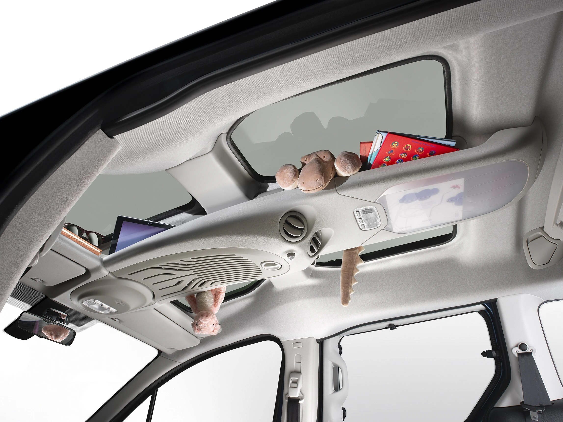 Auto-Innenraum mit Panoramadach, Stofftieren und Comic-Heft im oberen Stauraum. Moderne, helle Gestaltung mit Sicht auf den Himmel.