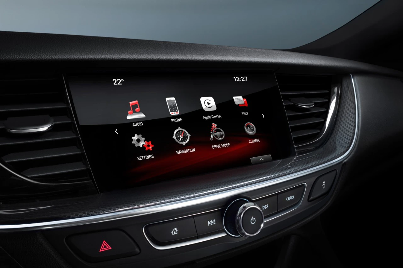 Infotainmentsystem eines Autos, zeigt Menüsymbole wie Navigation, Audio, Telefon, Apple CarPlay und Einstellungen auf einem Bildschirm.