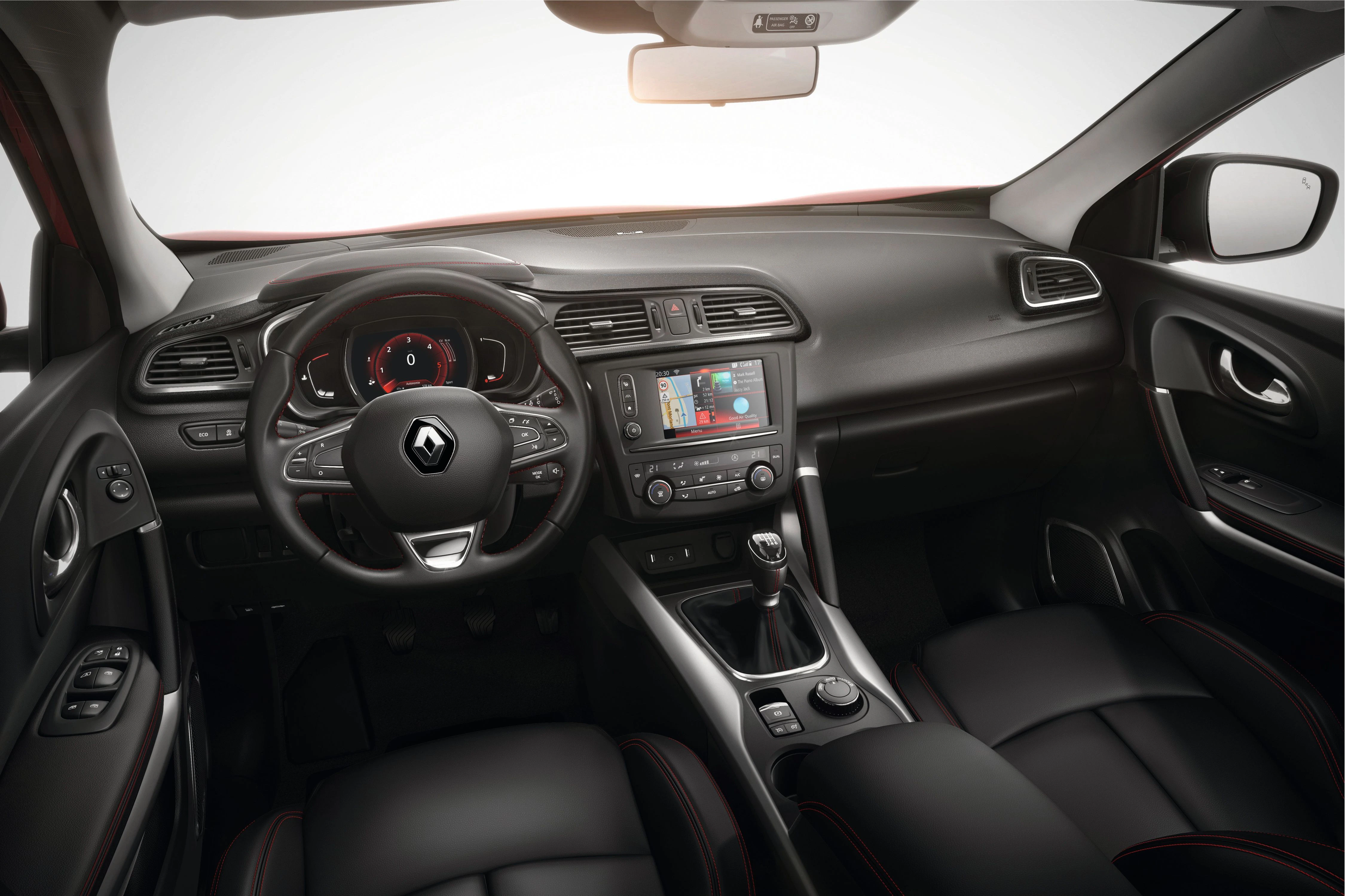 Innenraum eines Renault Autos mit schwarzem Leder, Infotainment-Bildschirm, Lenkrad mit Logo und modernen Bedienelementen.