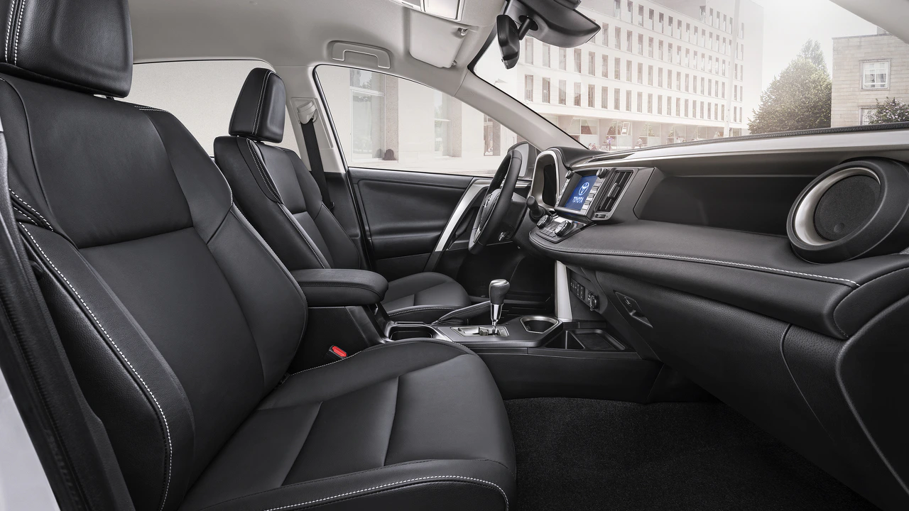 Innenraum eines modernen Autos mit schwarzen Ledersitzen und zentralem Touchscreen-Display. Helle Fensterfront im Hintergrund.