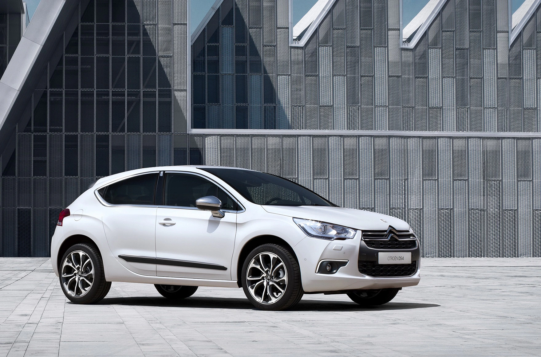 Weißer Citroën DS4 steht auf einem modernen, architektonischen Hintergrund mit futuristisch wirkenden Gebäudestrukturen.