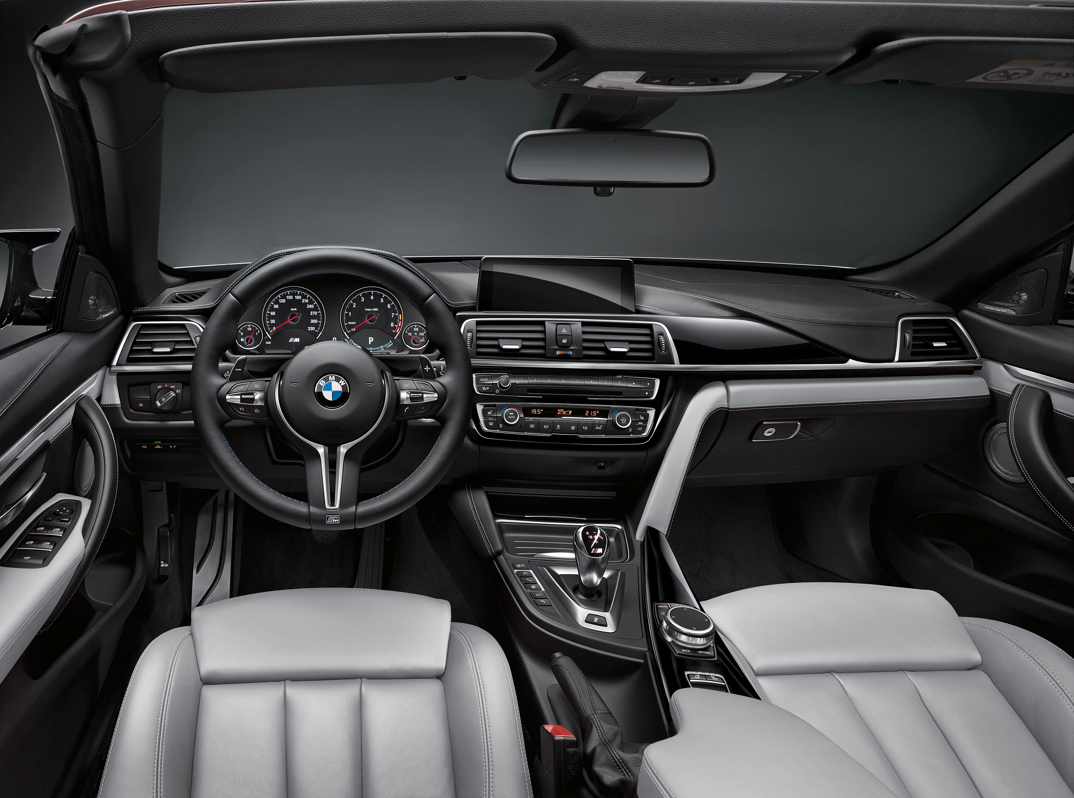 Innenraum eines modernen BMW-Autos mit Lederpolstern, Multifunktionslenkrad, Touchscreen-Display und eleganten Armaturen.