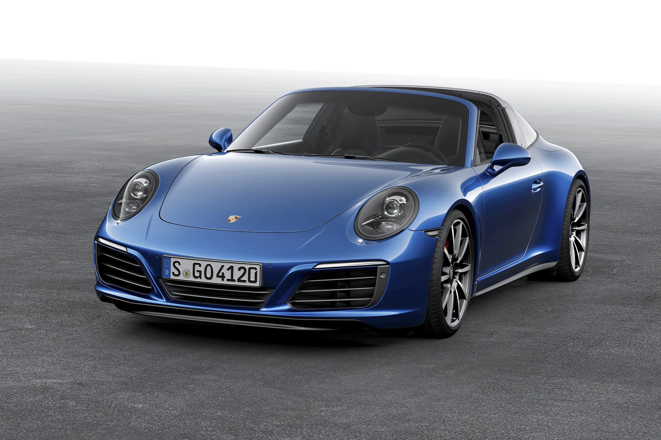 Blauer Sportwagen, wahrscheinlich ein Porsche, steht auf einem grauen Untergrund. Fahrzeug mit eleganten Linien und markantem Design.