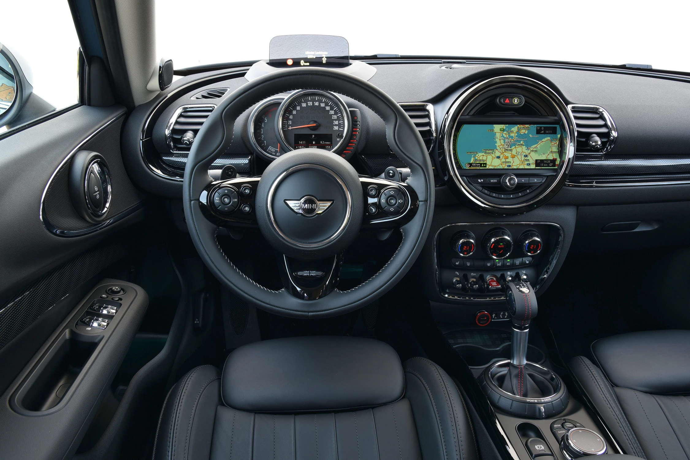 Innenraum eines Autos mit Lederlenkrad, digitalem Armaturenbrett und Navigationssystem auf einem Bildschirm in der Mittelkonsole.