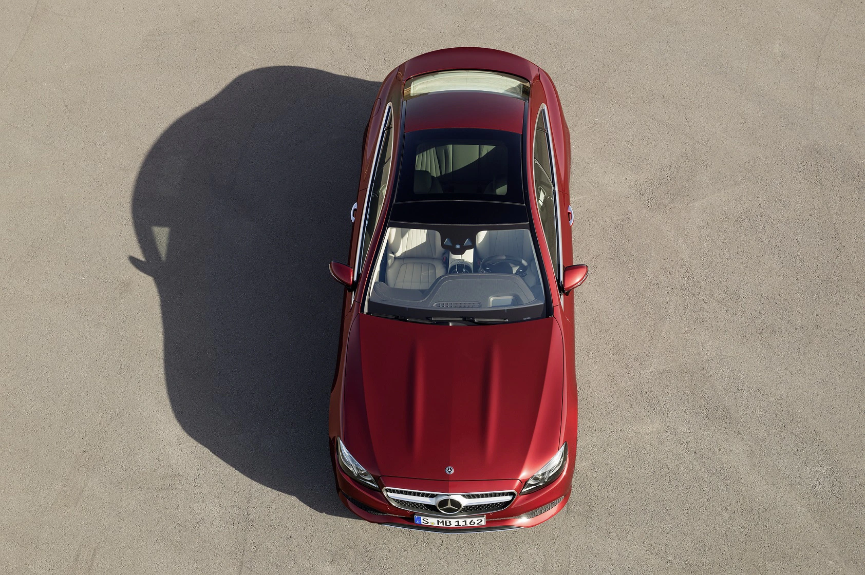 Roter Mercedes-Benz von oben, auf einer asphaltierten Fläche geparkt, mit Schiebedach und hellem Innenraum.