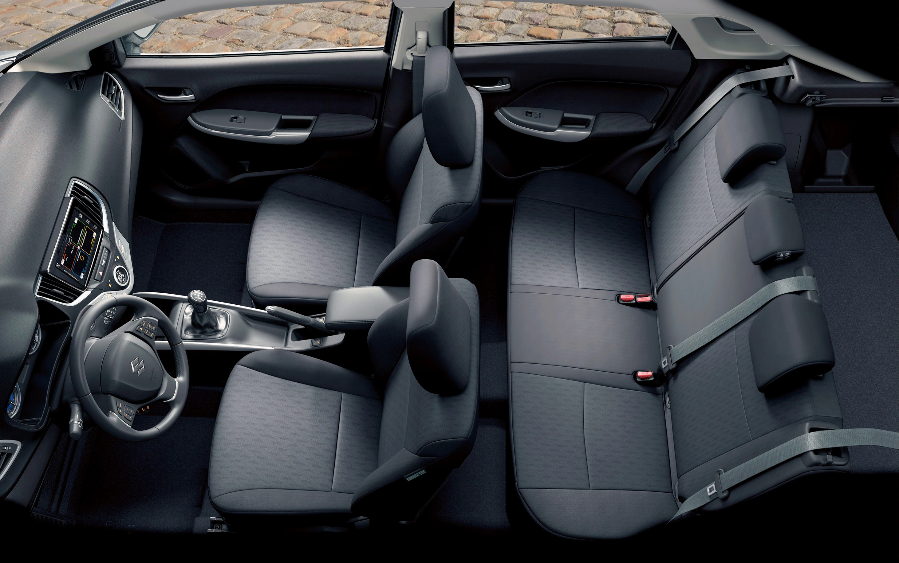 Innenraum eines modernen Autos von oben, mit schwarzen Stoffpolstern, Mittelkonsole mit Schalthebel und Anzeige, und drei Rücksitzen.